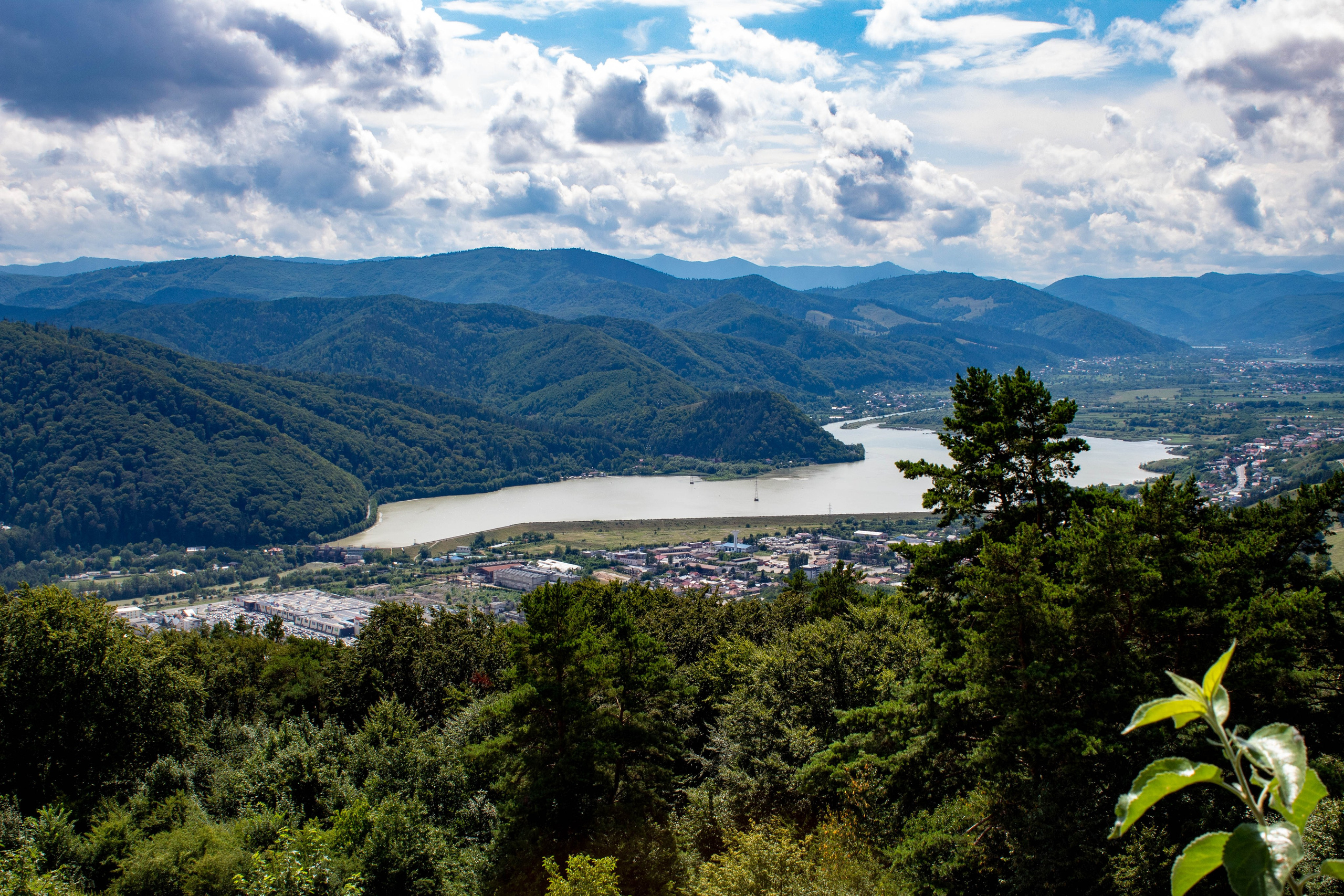 Elevated view of forested hills under a sky with large drifting clouds.