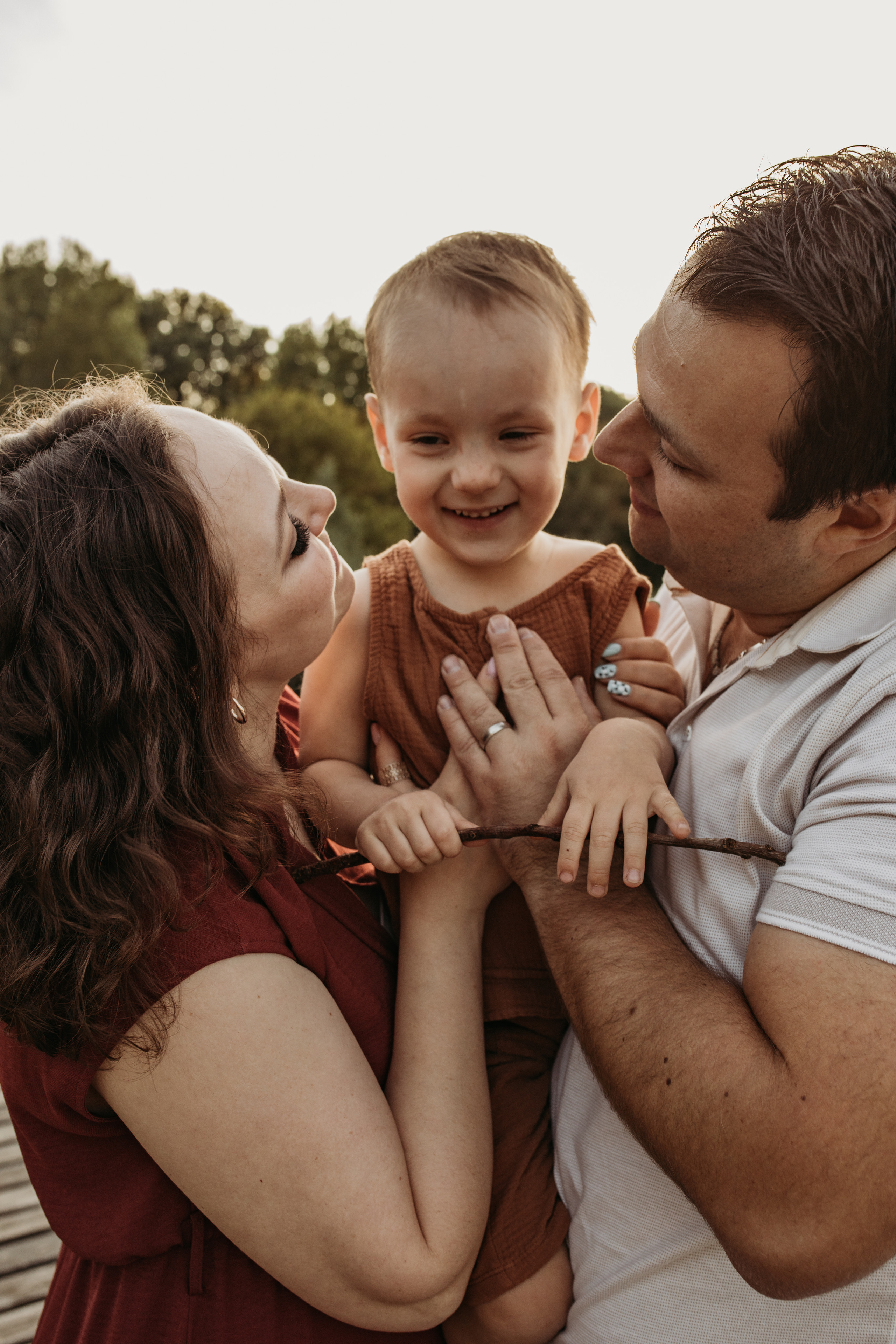 Glückliche Eltern lächeln  ihren Sohn an bei Familienfotografie in Heidelberg.