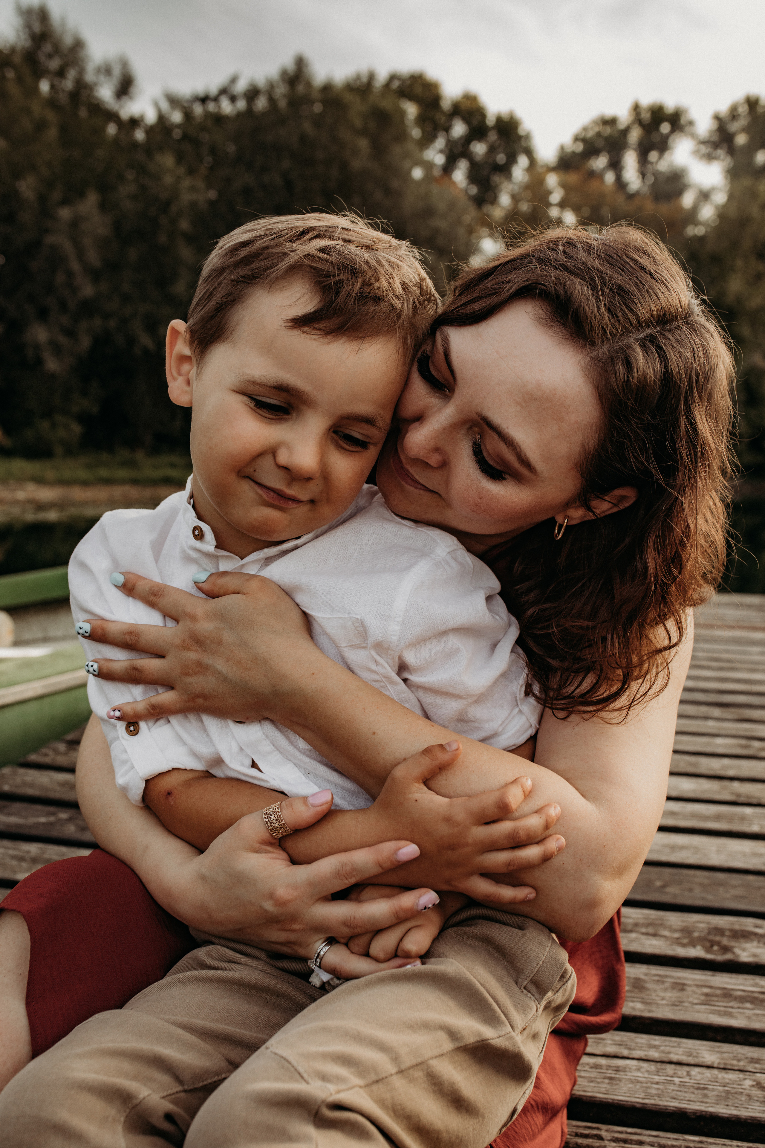 Mama hält liebevoll ihren Sohn auf dem Schoss bei Familienfotografie auf dem Steig.