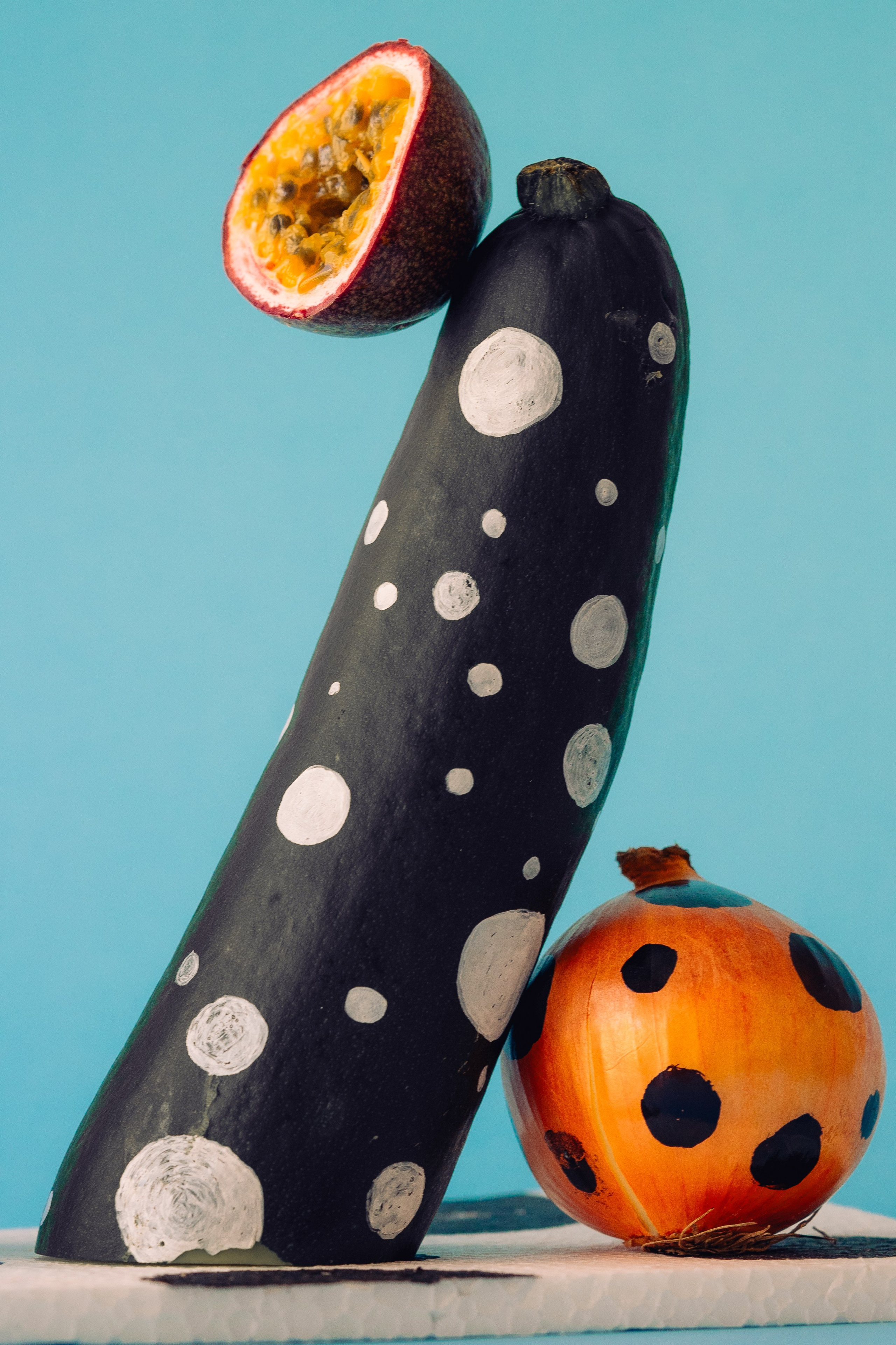 Arranjo da arte vegetal pintada pontilhada do projeto.  Exposição criativa dos vegetais pintados pontilhados do projeto em um fundo azul brilhante.