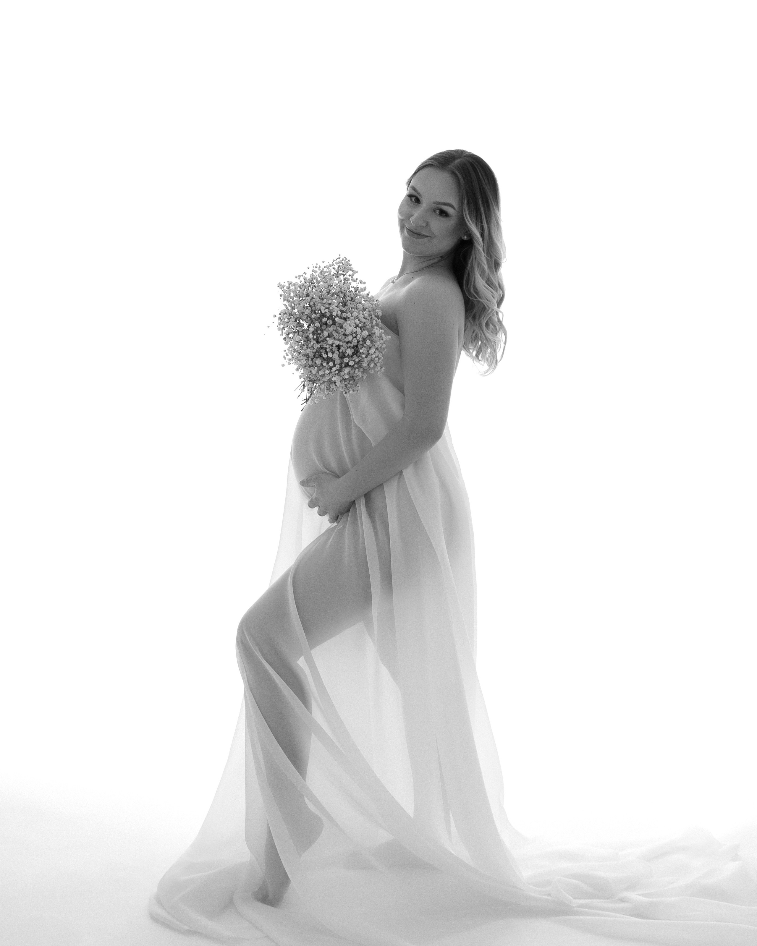 Künstlerisches Schwangerschaftsfoto mit transparentem Tuch und natürlichem Ausdruck