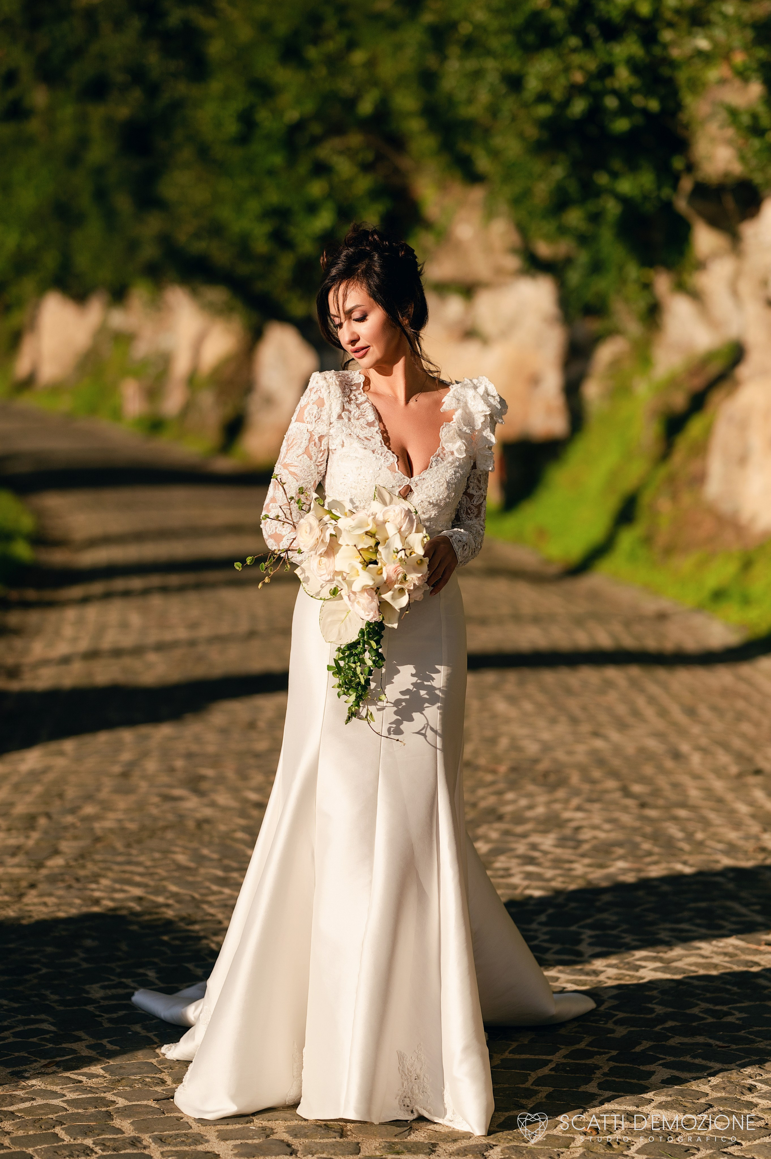 sposa sul viale alberato verde sotto il sole con bouquet in mano