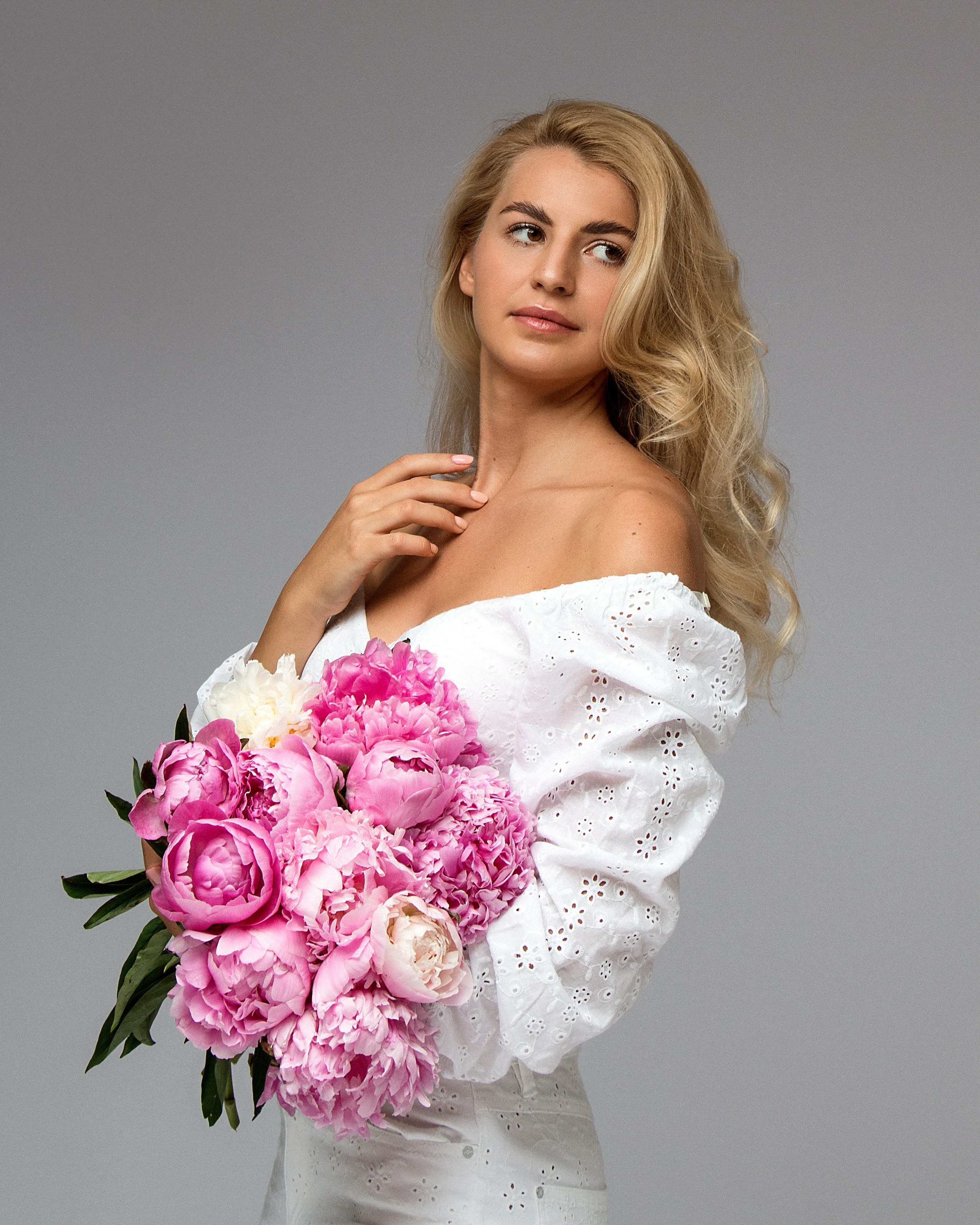 Ästhetische Aufnahme einer Blondine mit Pfingstrosen in hellem Ambiente