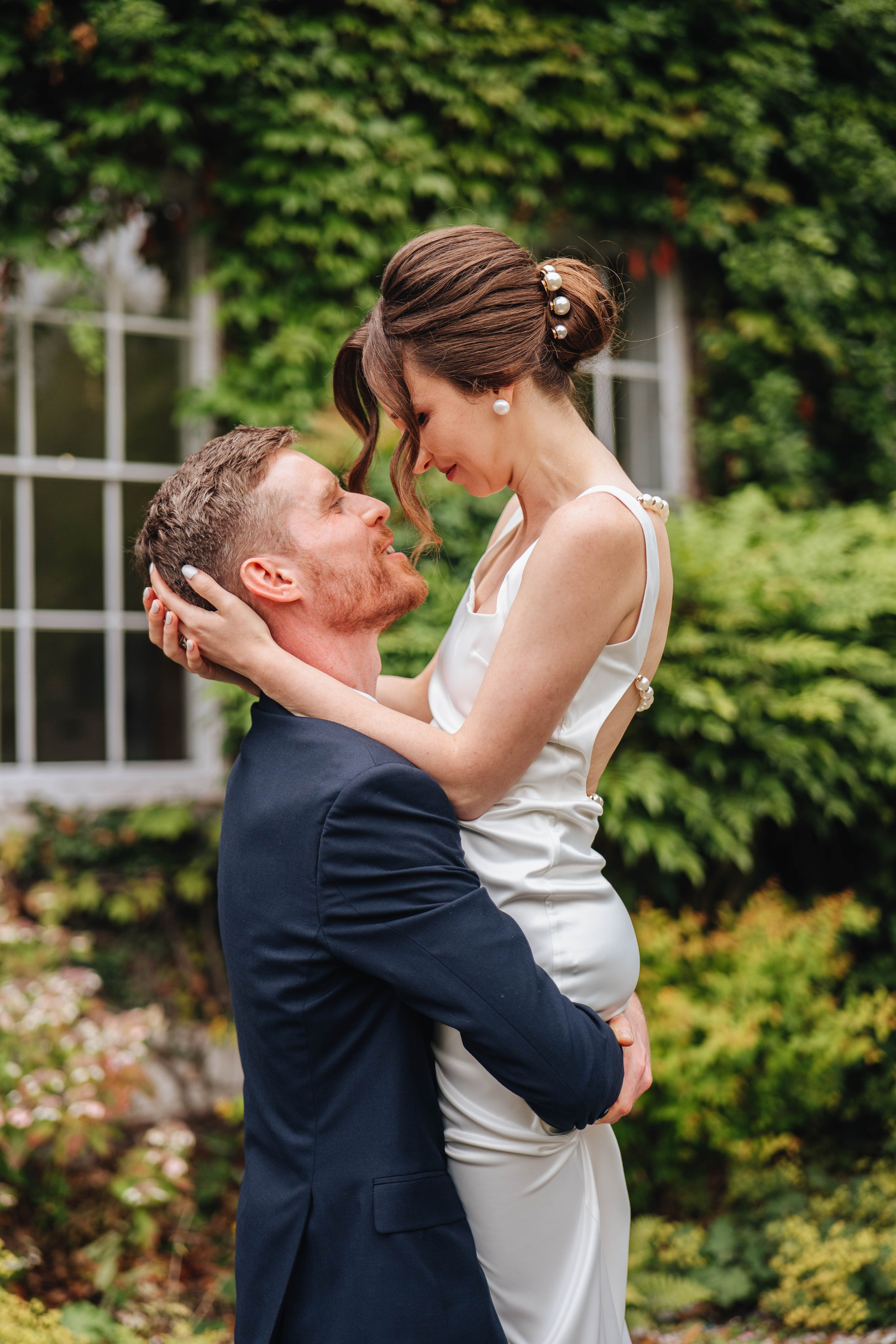 groom lifts and holds the bride on the greenish background