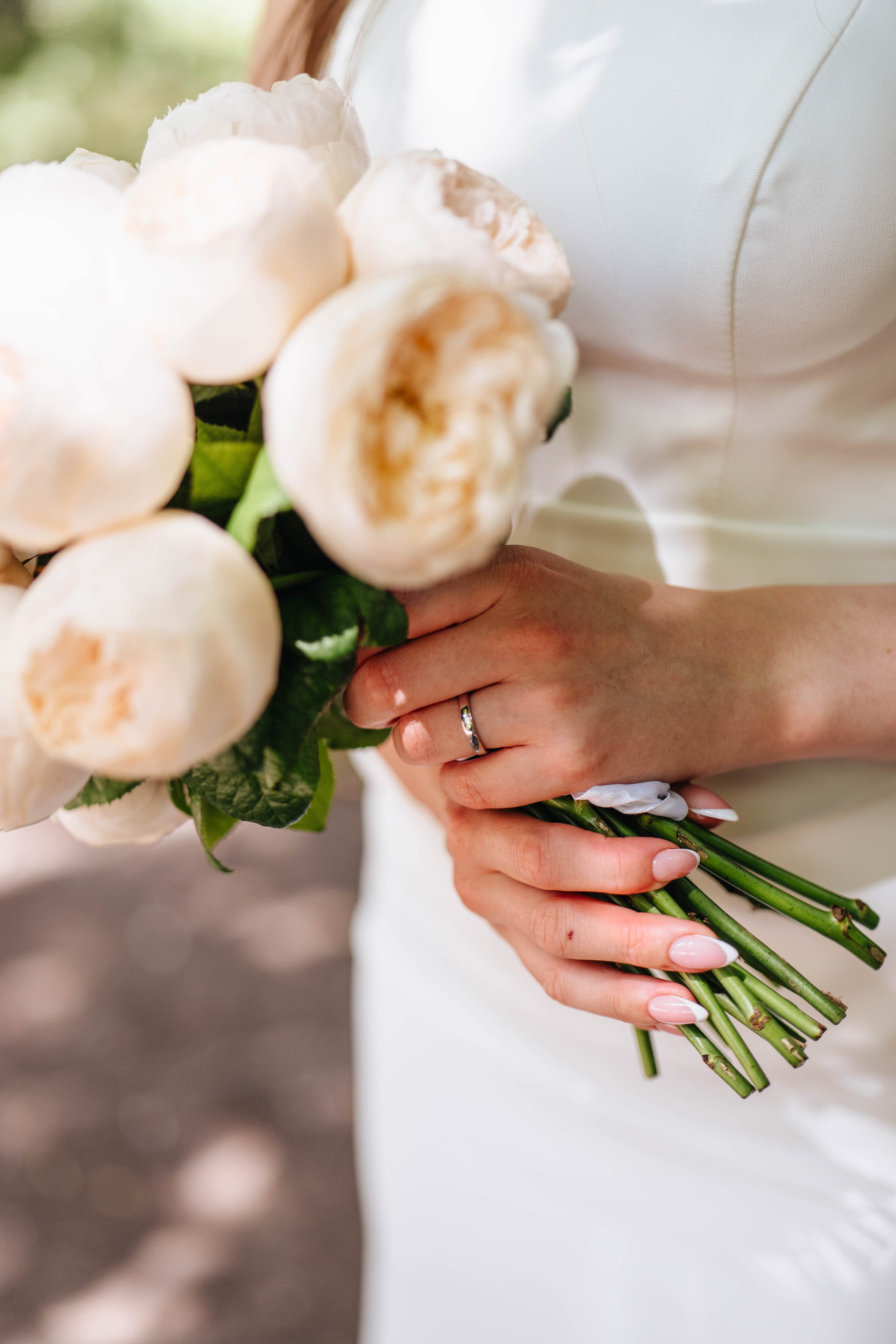 close up of bride's hands with flowers in the summer park