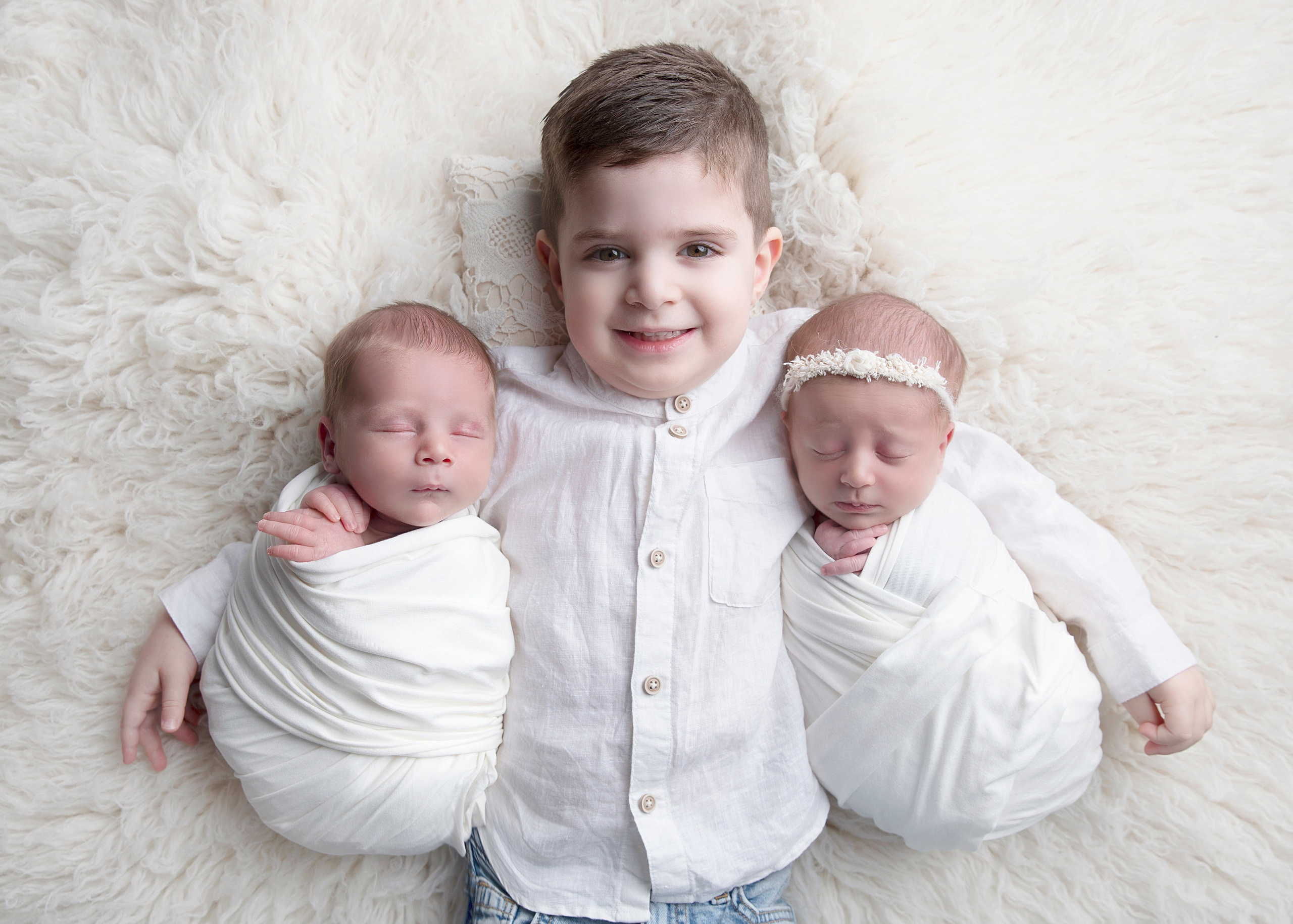 Två nyfödda tvillingar som ligger tillsammans i en mjuk filt. Bilden fångar deras söta och harmoniska utseende, perfekt för att illustrera tvillingfotografi och nyfödda bilder."