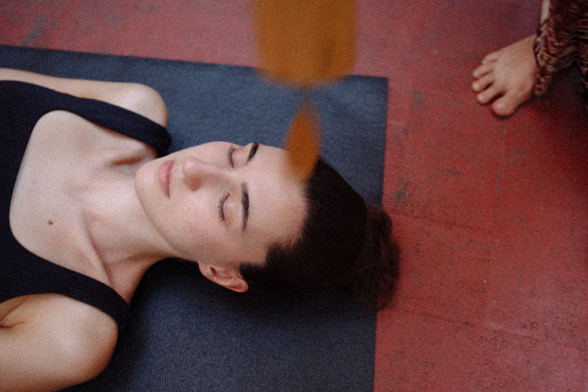 Woman lying calmly on a blue mat, eyes closed and peaceful expression