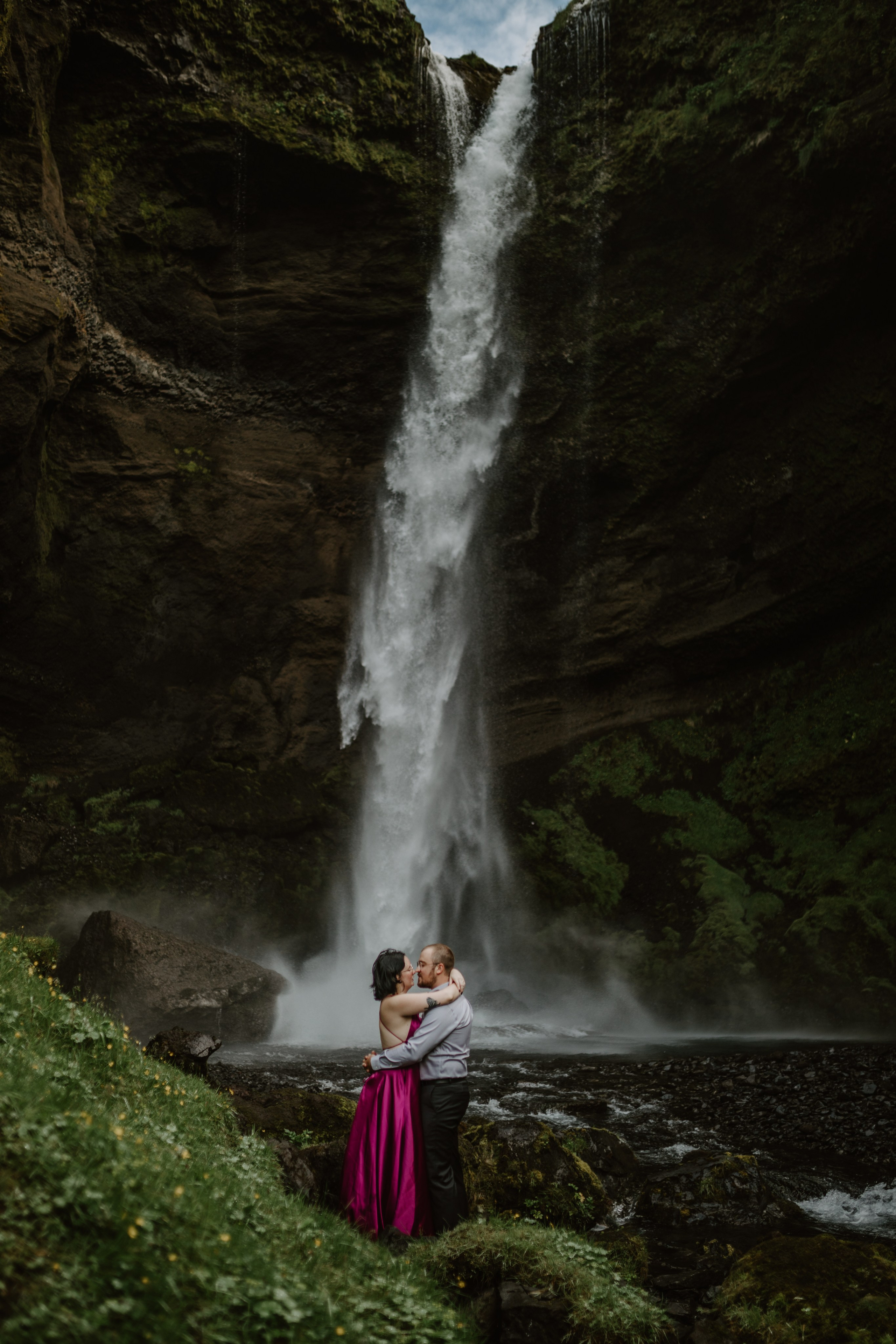 Love in the wild—couple sharing a quiet moment in front of a majestic Icelandic waterfall.