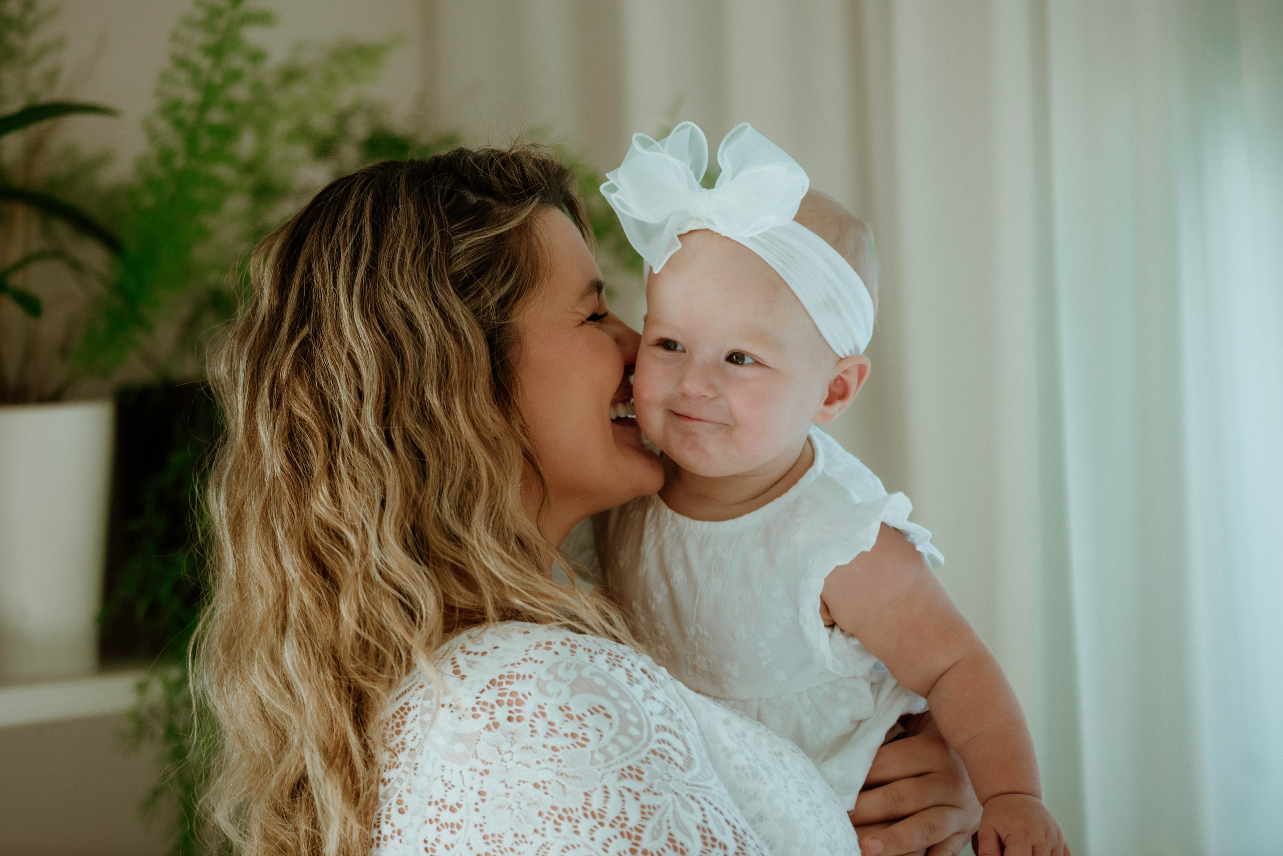 An enchanting outdoor maternity photoshoot at the client's house. The image features a radiant mother and her daughter, both elegantly dressed in white, against the backdrop of their home. The simplicity of their attire and the natural surroundings creates a timeless and intimate atmosphere. Book a personalized outdoor session with MD Studio to capture beautiful moments in the comfort of your own home