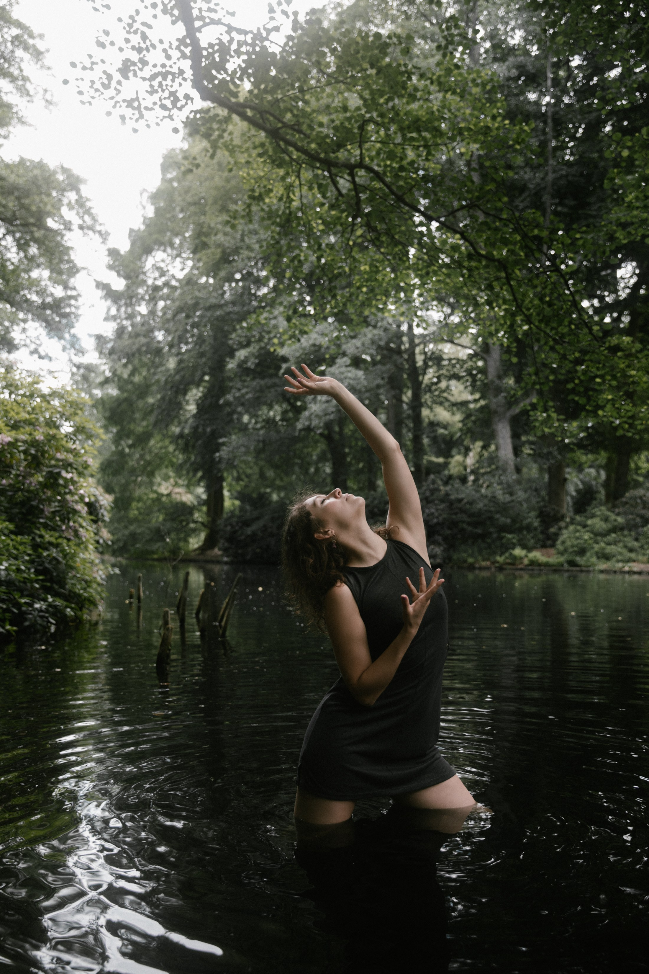 Frau in tanzähnlicher Pose am Waldteich