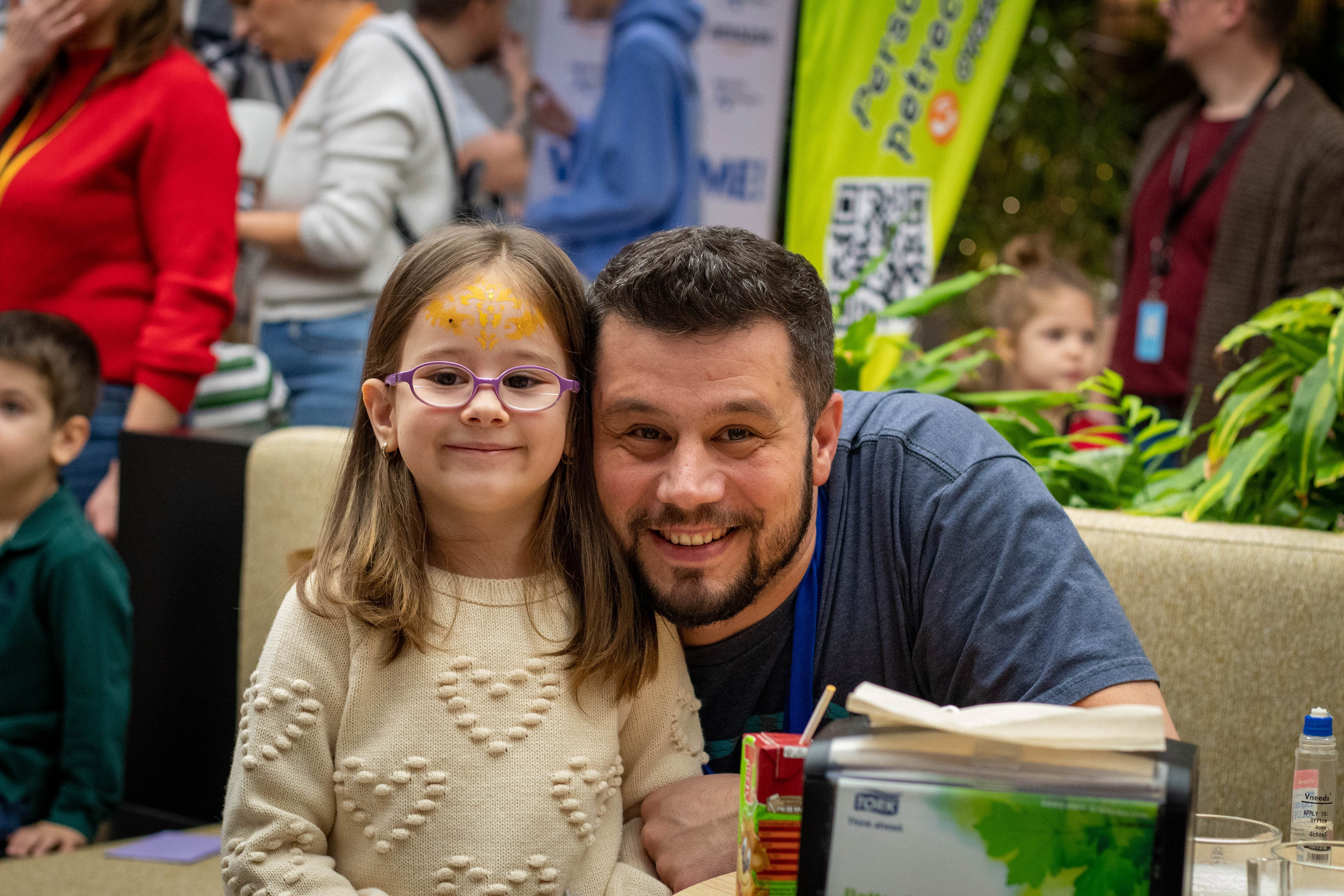 Parents and child cuddling and laughing on the grass in a candid outdoor photo.