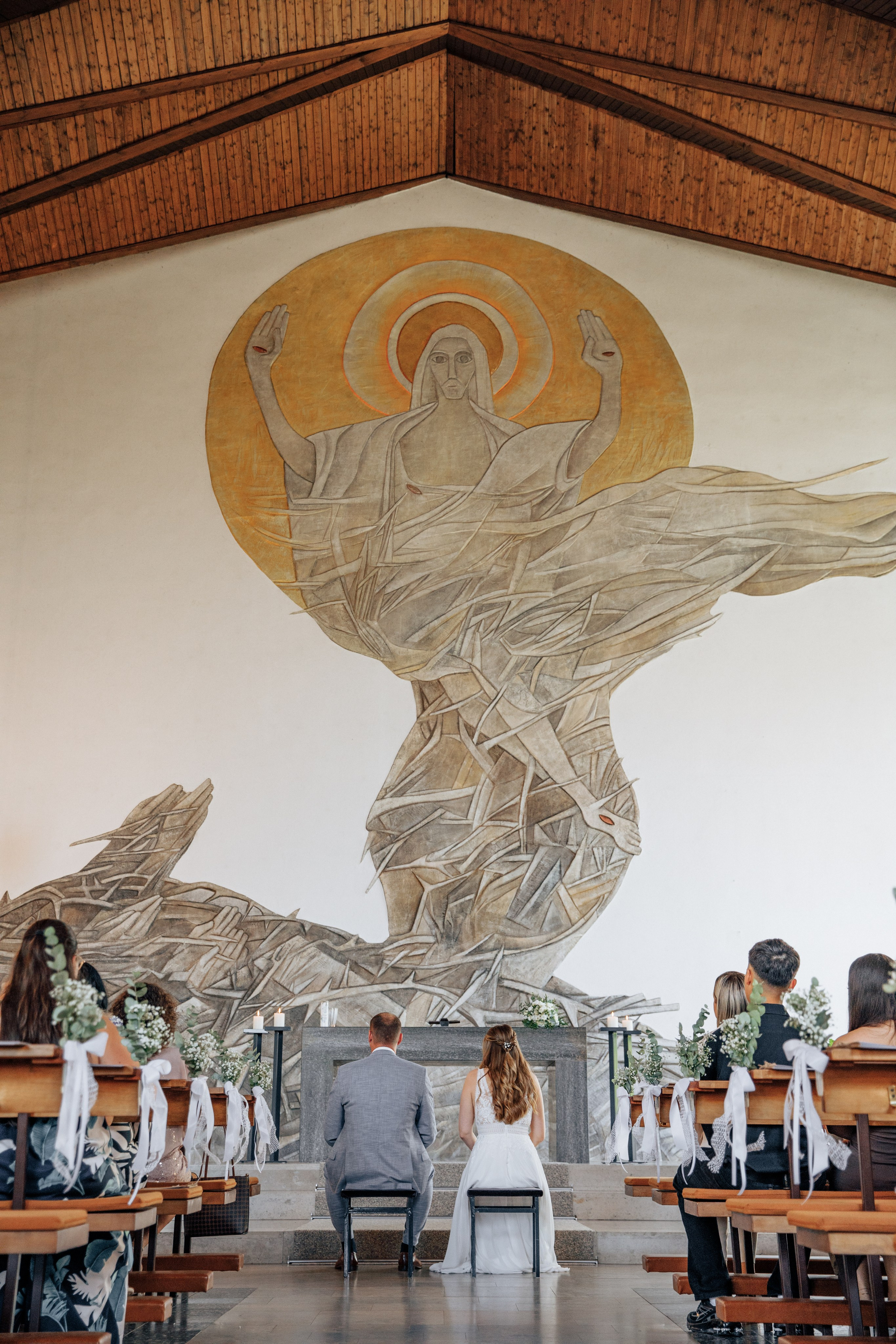 Der Bräutigam und die Braut sitzen in der Kirche vor dem Altar mit einem Bild von Jesus in Soden.