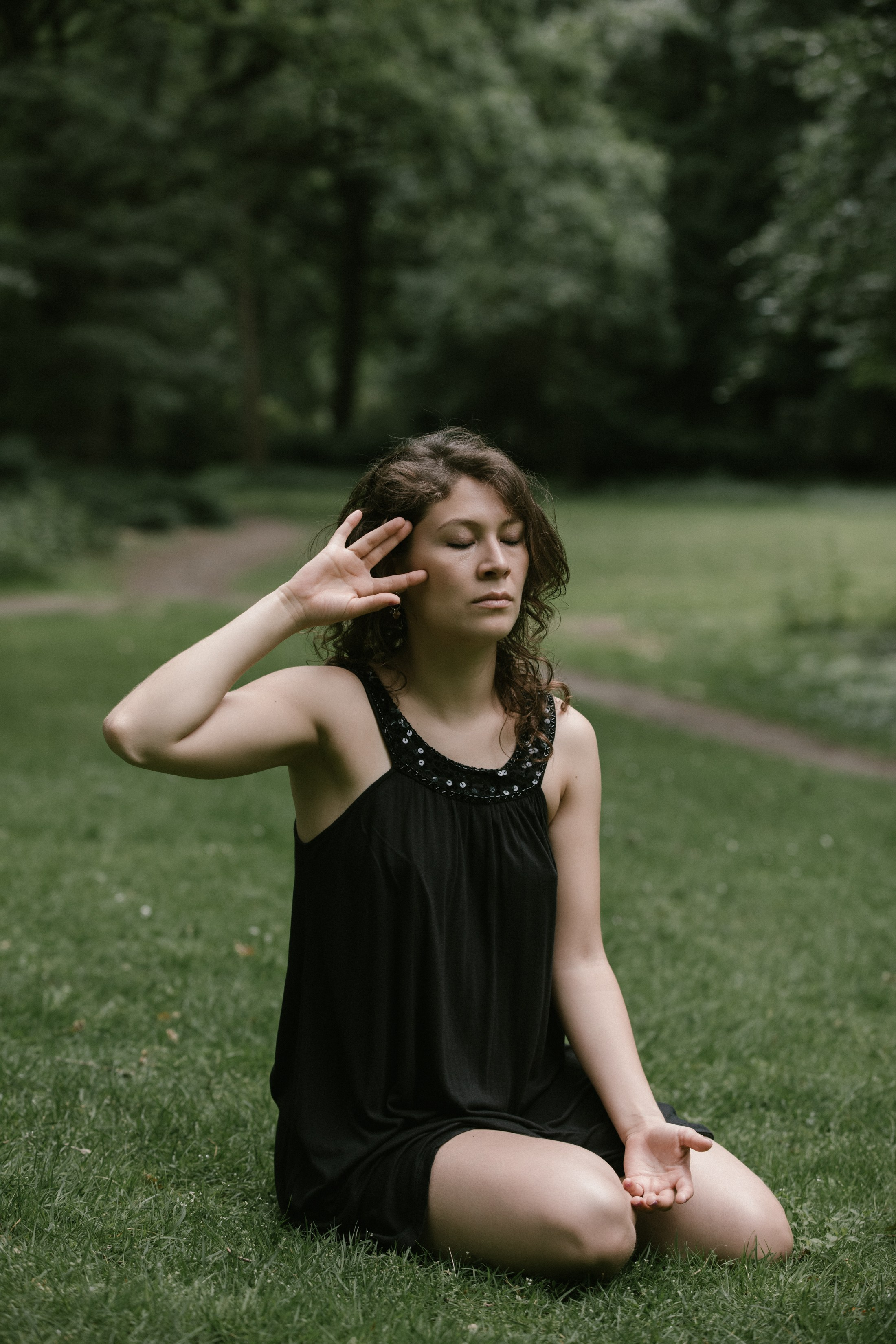 Geschlossene Augen, Tänzerin in sitzender Pose im Gras