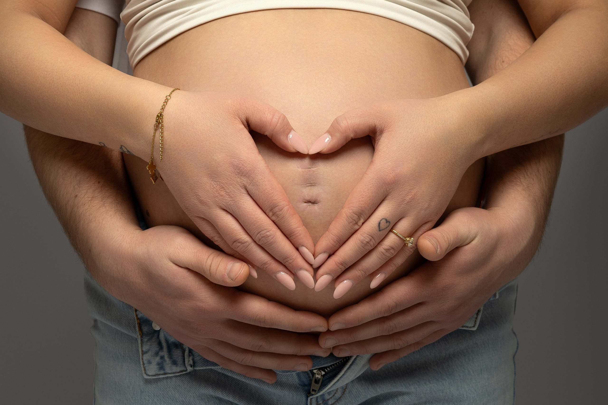 Zärtlicher Moment zwischen werdenden Eltern – Hände auf dem Babybauch