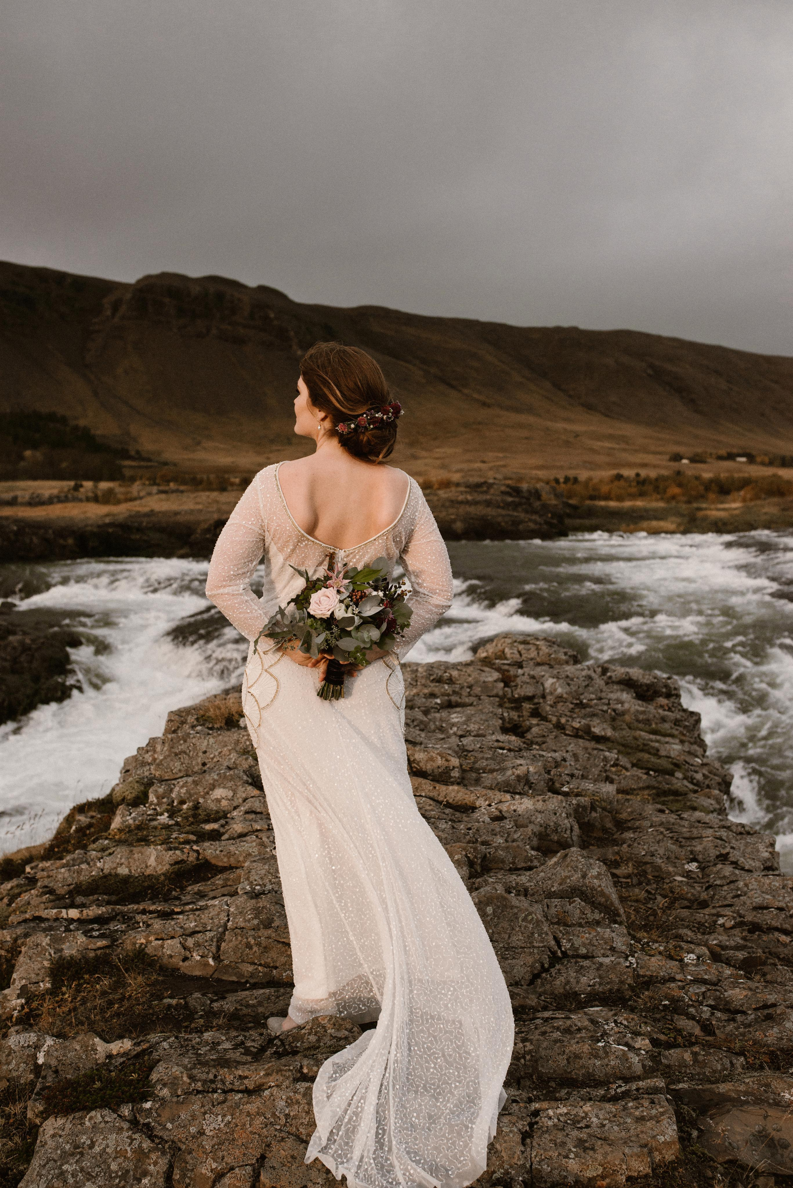 Bride and groom sharing a kiss beneath the cascading waters of Kvernufoss, tucked away in a hidden Icelandic valley.