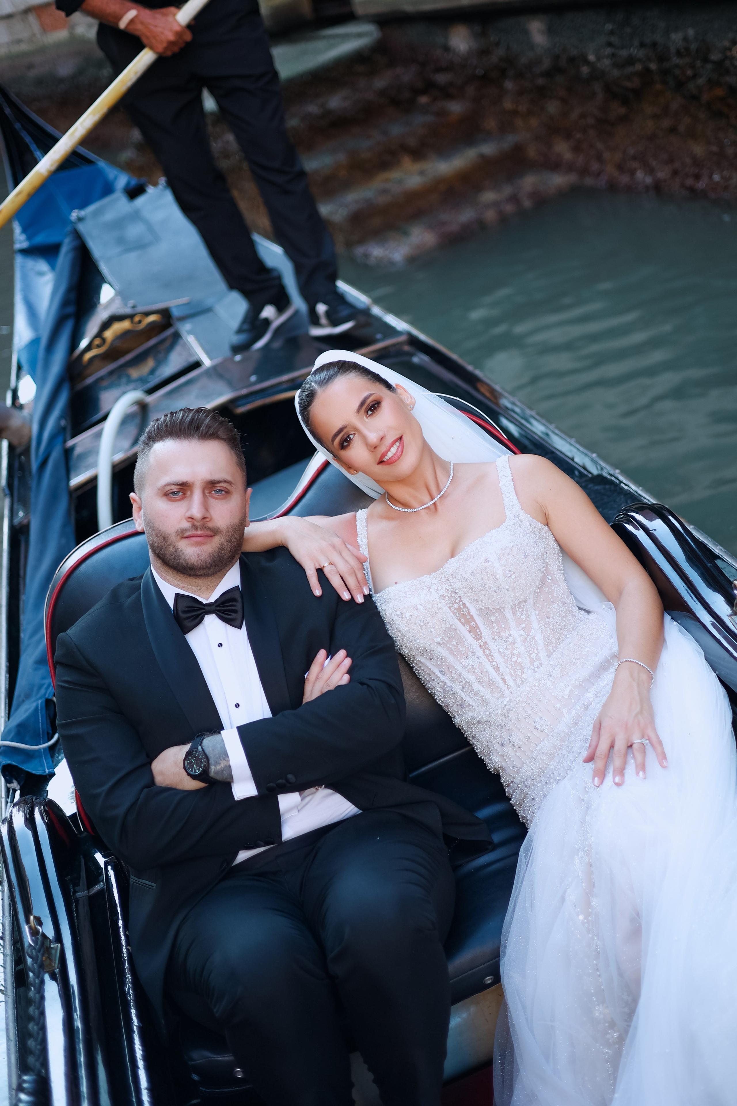 Romantic portrait of a bride and groom by a gondola docked along the Venetian canals