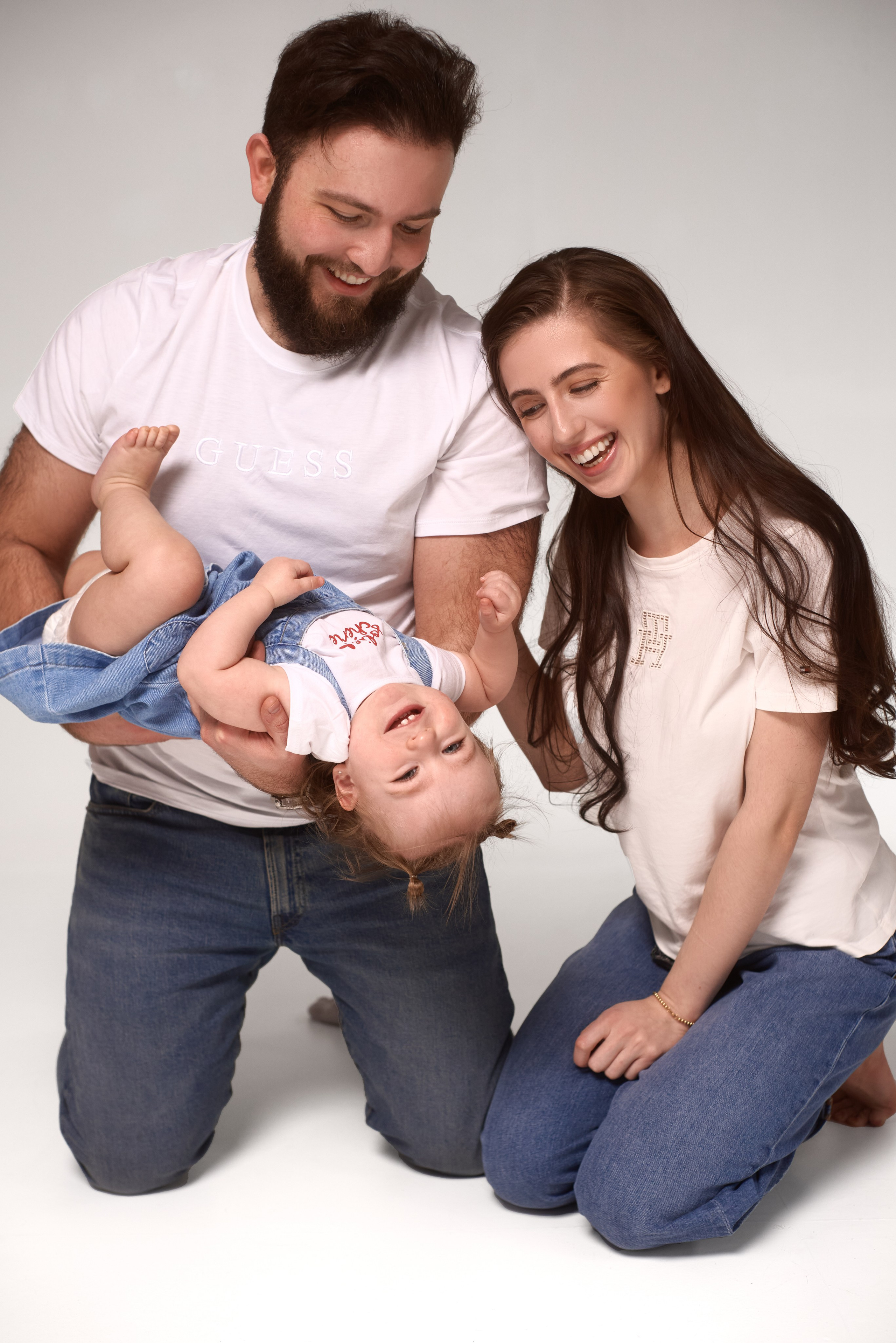 Rodzinne zdjęcia pełne radości – rodzice bawiący się z dzieckiem podczas studyjnej sesji fotograficznej