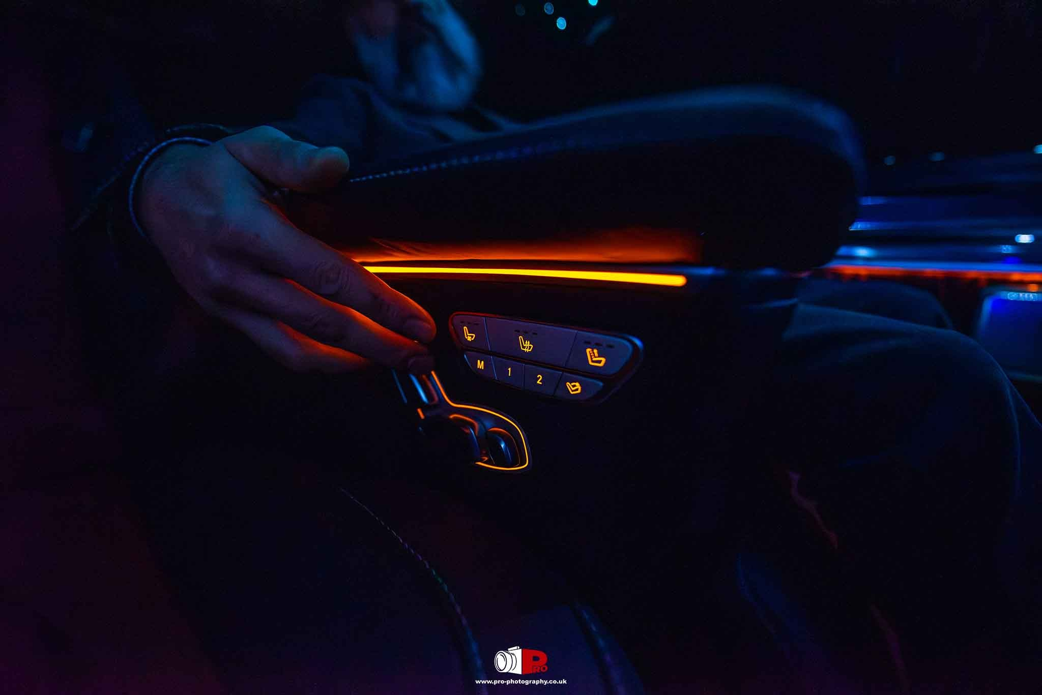 Close-up of a high-end car armrest featuring illuminated seat controls and ergonomic design.