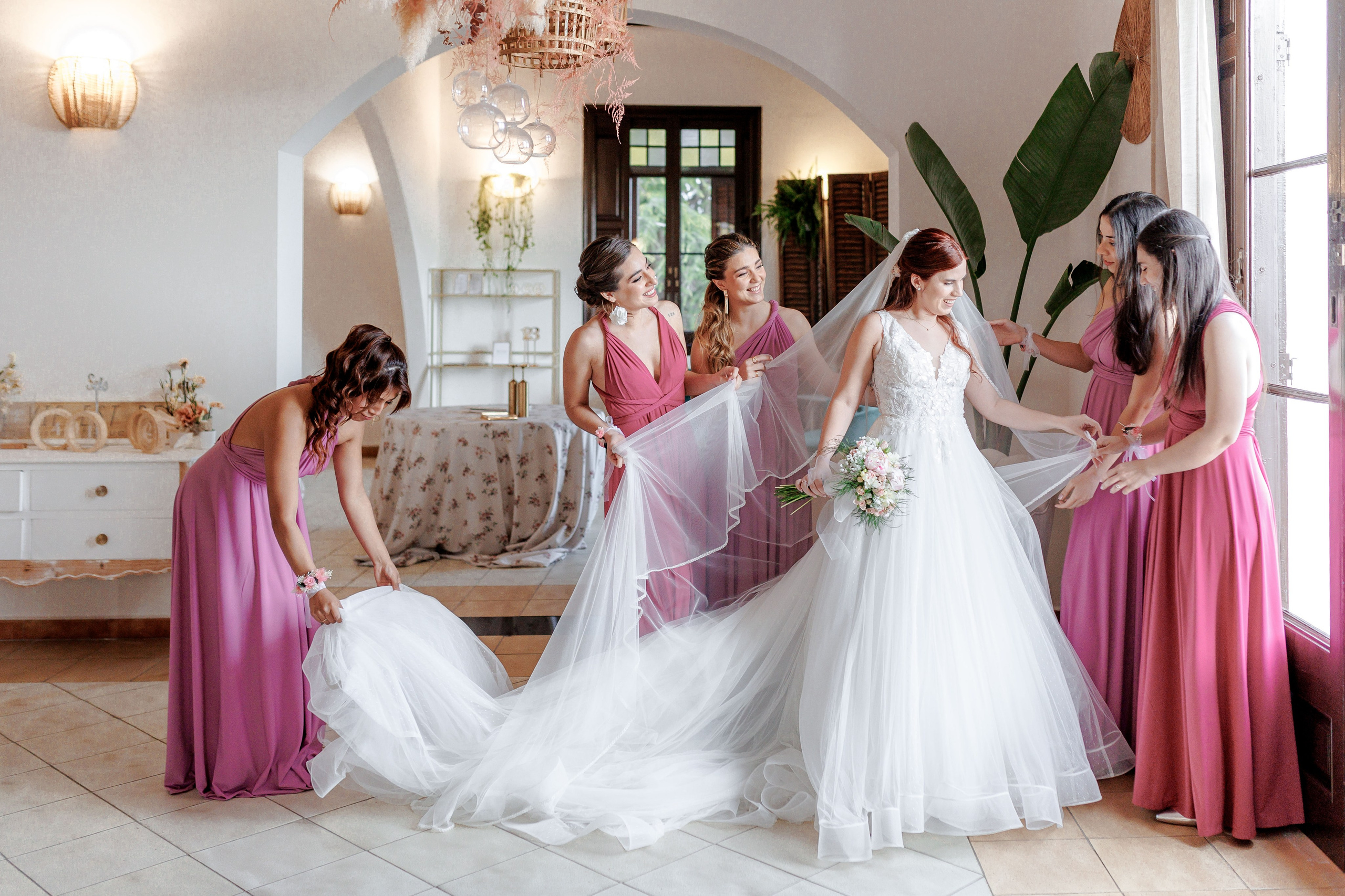 Bride surrounded by bridesmaids who adjusting her dress and preparing for the ceremony.