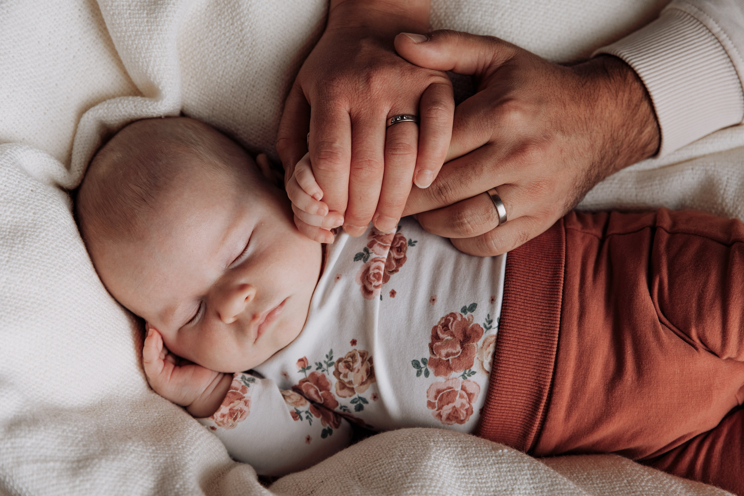 Hände von Vater und Mutter liegen sanft auf ihrem Baby.