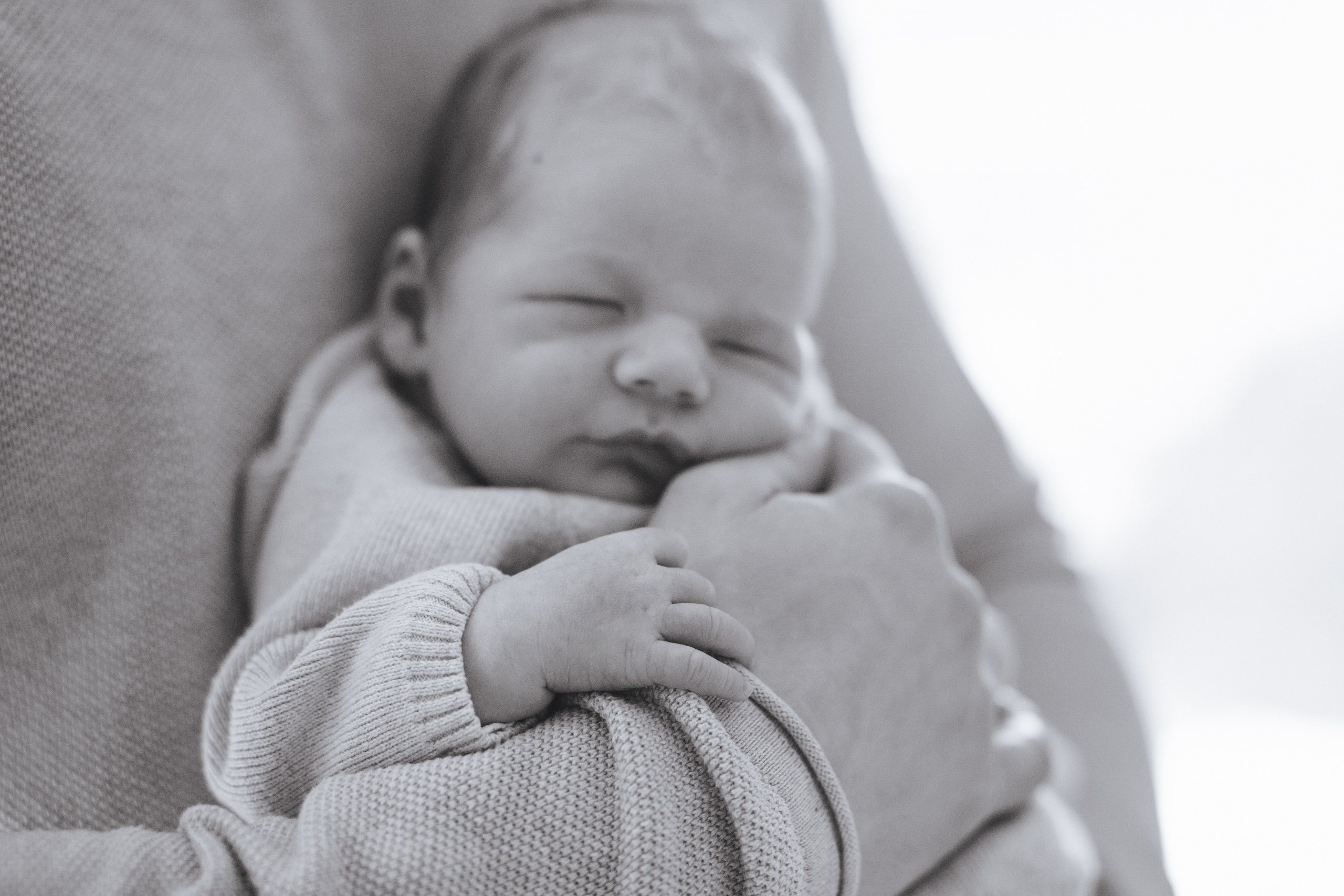 Neugeborenes liegt zart auf dem Arm seines Vaters während eines liebevollen Newborn-Fotoshootings.