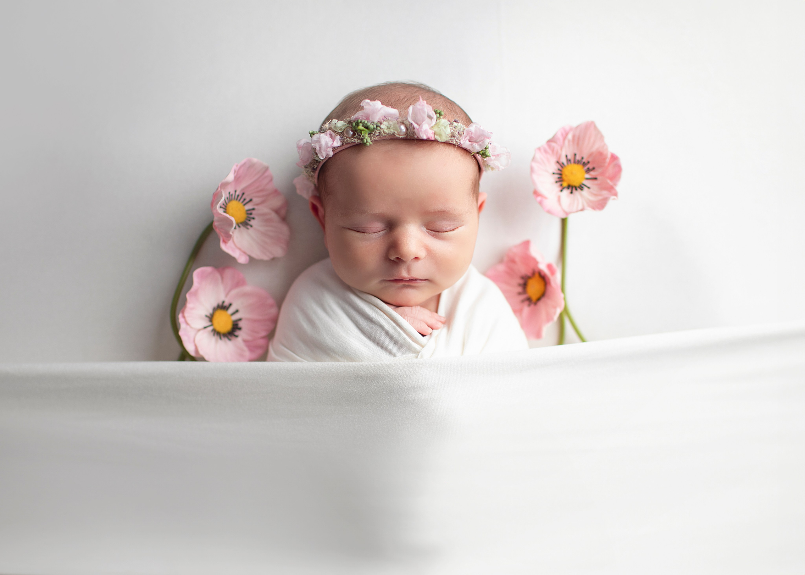 "Söt nyfödd baby som ligger i en mjuk filt med ett lugnt uttryck. Bilden är utmärkt för webbplatser som fokuserar på babyfotografi och nyfödda bilder."