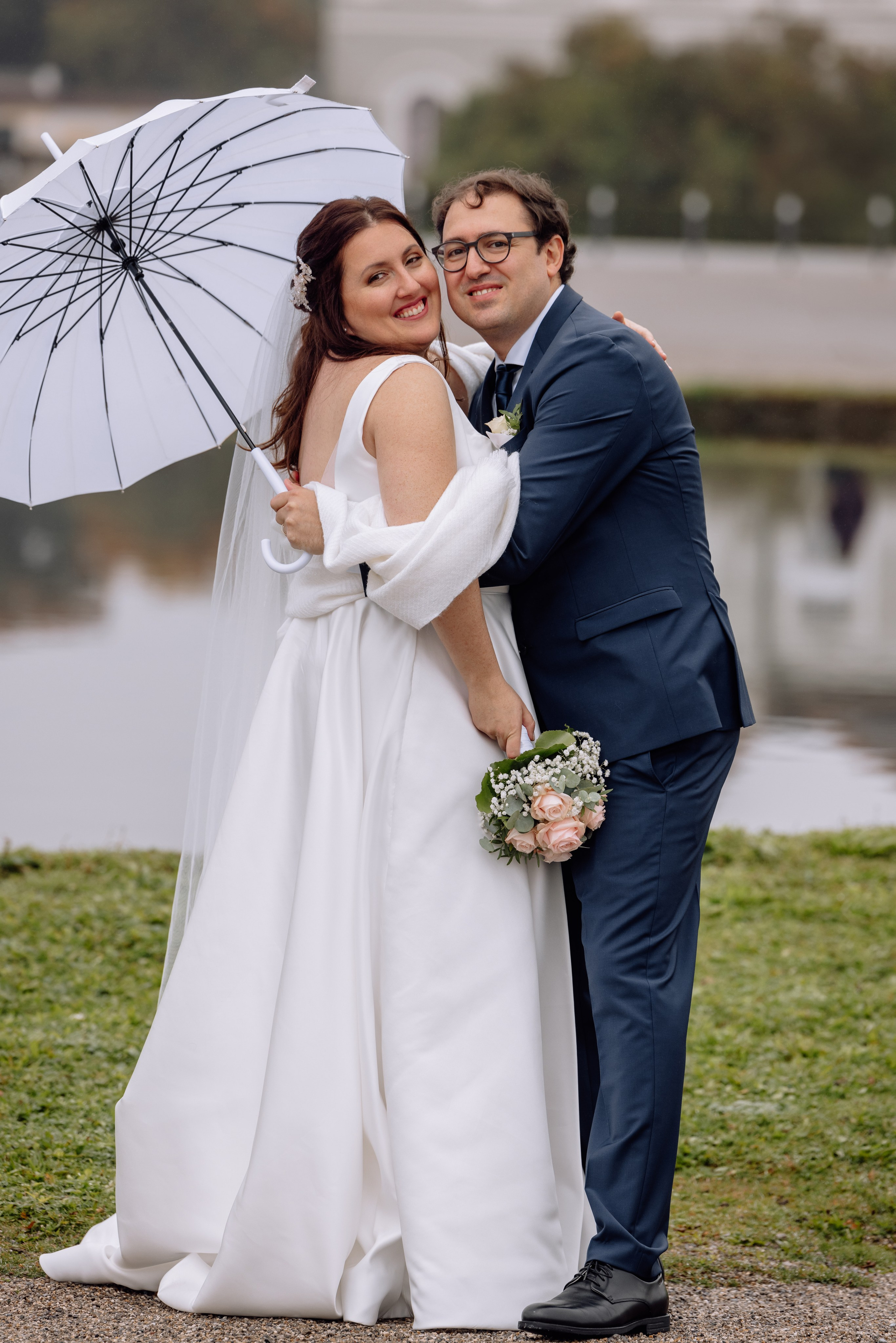 Das Paar unter einem Regenschirm auf Hochzeitsfotos vor dem Schloss Nymphenburg