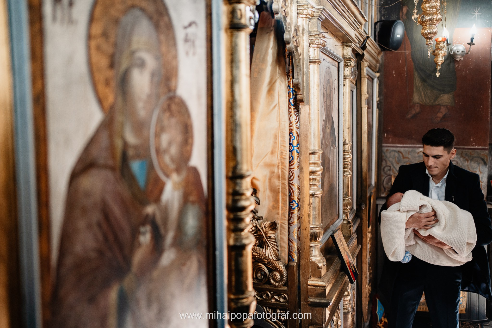 Instantaneu plin de tandrețe dintre părinți și bebeluș în ziua botezului, realizat în ilfov. Fotografie profesională de botez, capturând emoțiile autentice ale familiei într-un decor luminos și cald