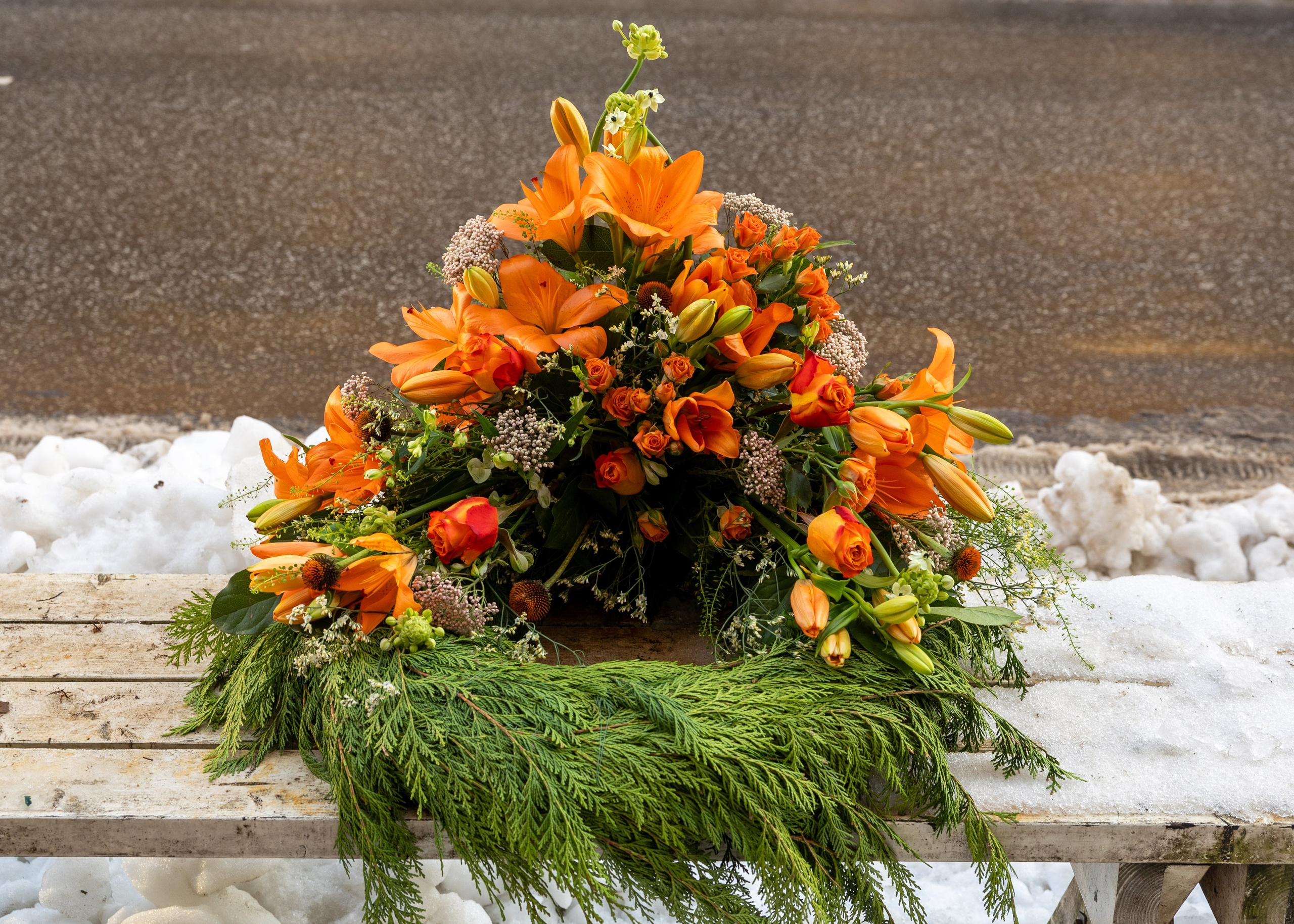 En elegant klassiker til den sidste afsked. Årstidens blomstersorter i høj og flot dekoration. Fastgjort på en grøn thujakrans. Denne krans med forskellige blomster tager sig smukt ud på kirkegulvet.
