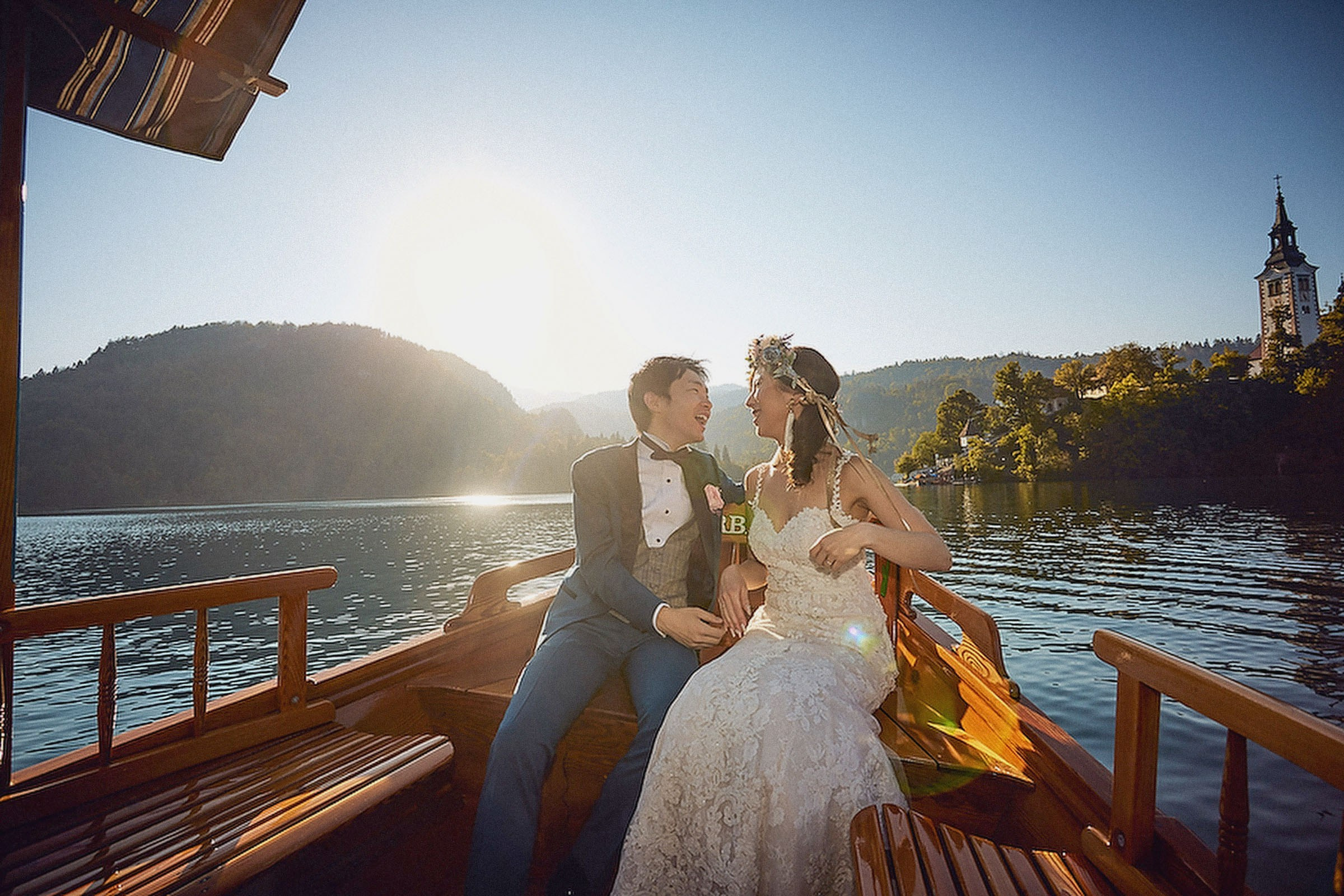 A serene image of a young Japanese bride and groom embracing on a boat bathed in the golden hues of the late afternoon sun.