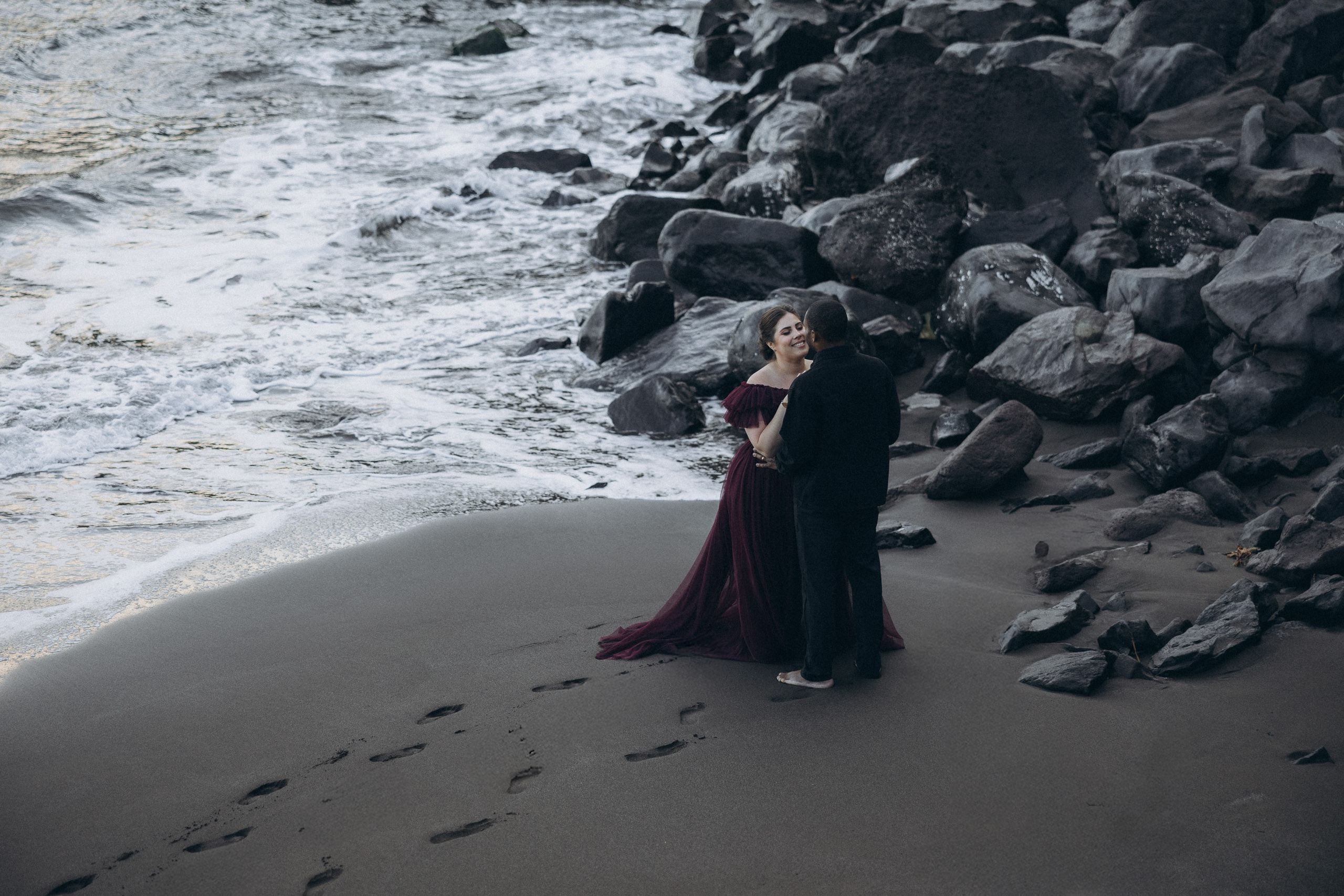 A glowing expectant mother standing on a cliff overlooking the ocean in Madeira, her dress flowing gently in the wind as the golden sunset casts a warm glow.