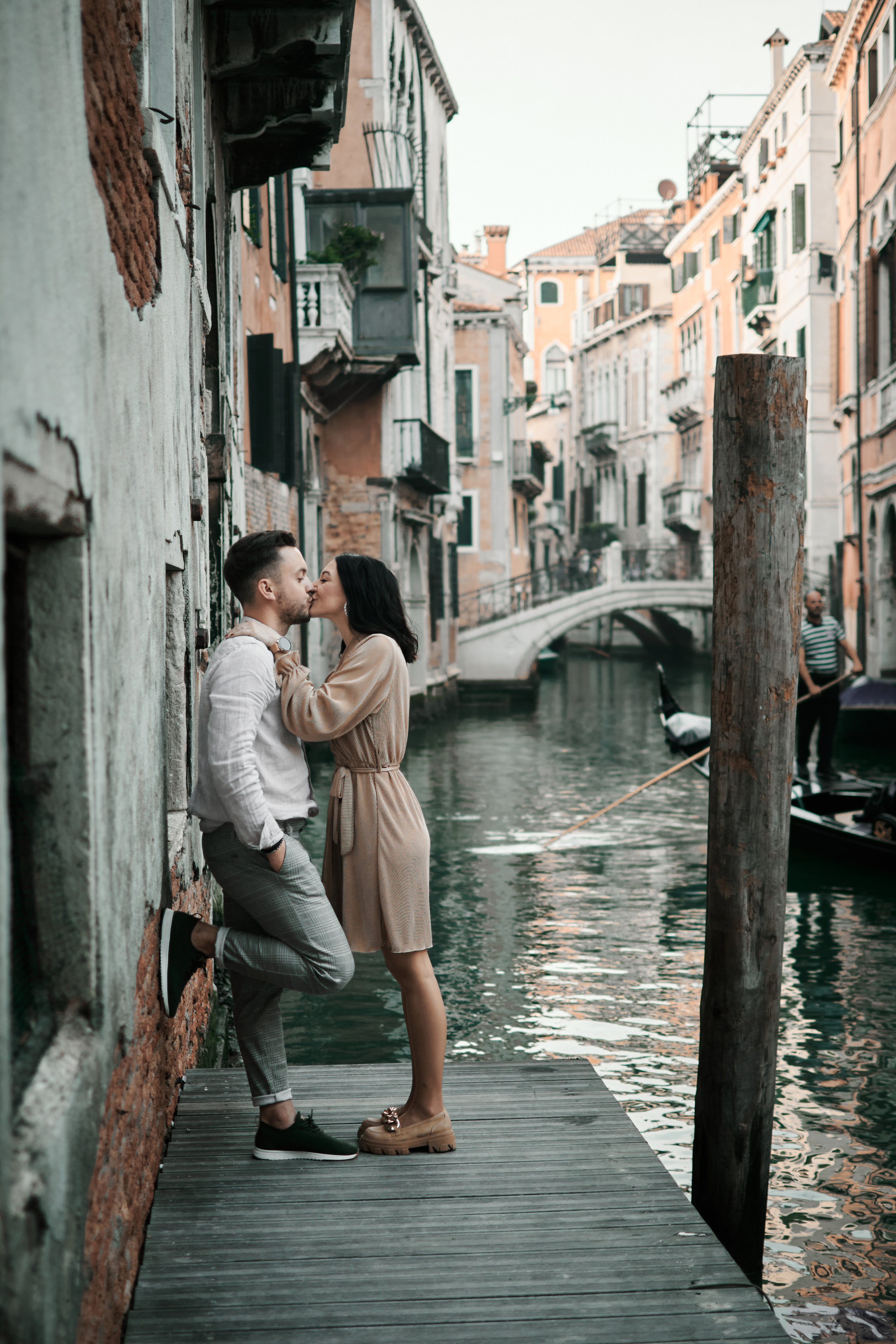 A newlywed couple stands hand in hand in front of a Venetian palace with the bride's veil billowing in the wind
