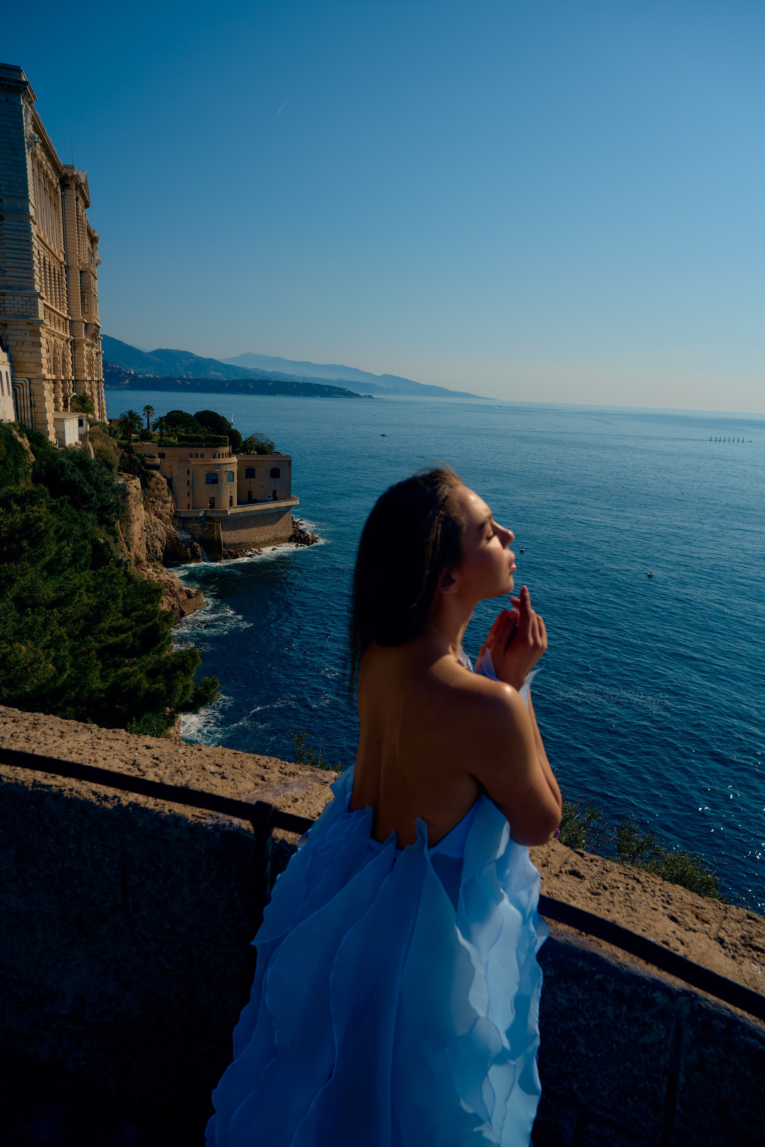 Outdoor fashion photo with blue dress and Monaco cityscape behind
