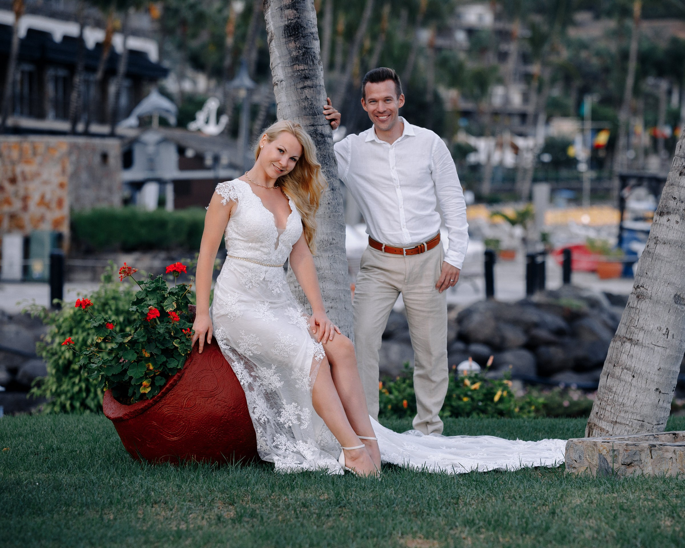A bride and groom posing in front of a palm tree.
