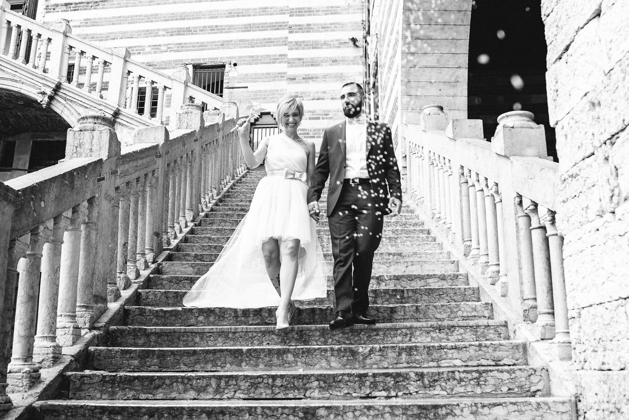 Счастливые молодожены спускаются по лестнице из Дворца бракосочетаний в Вероне