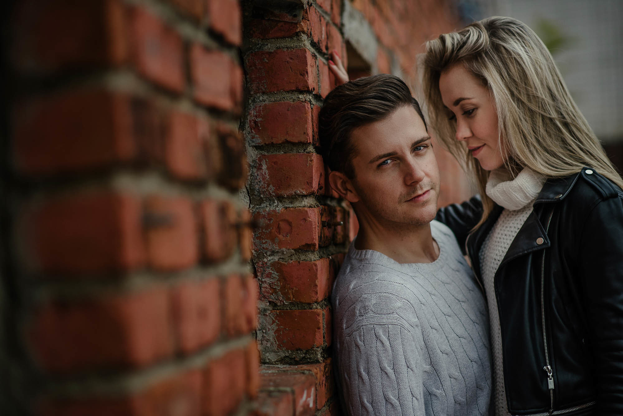 Женщина смотрит на своего любимого у стены из красного кирпича, lovestory фотосессия