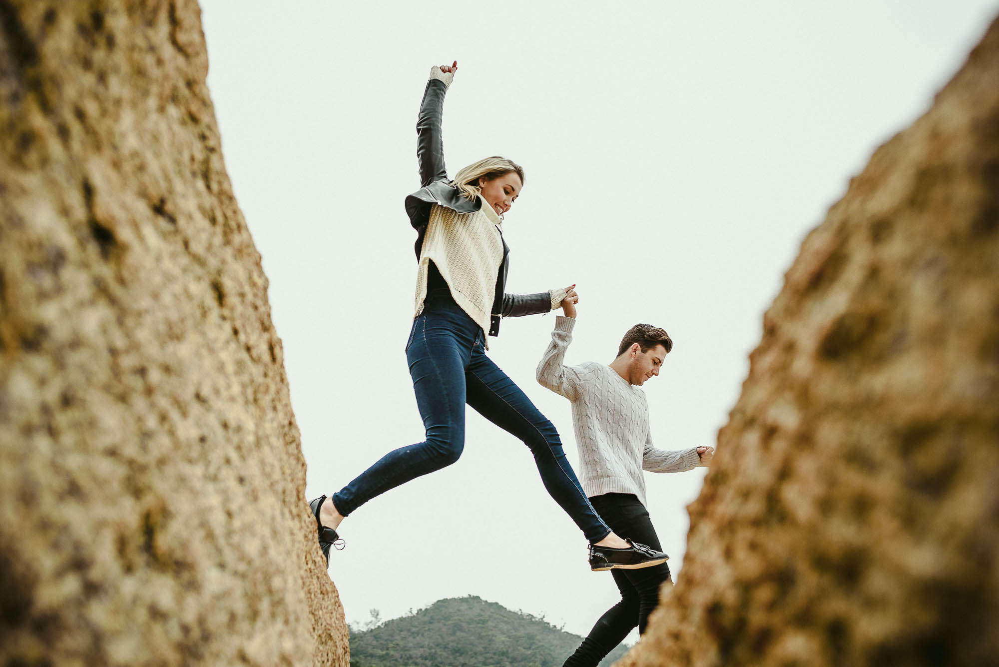 Девушка перепрыгивает с камня на камень, держась за руку любимого