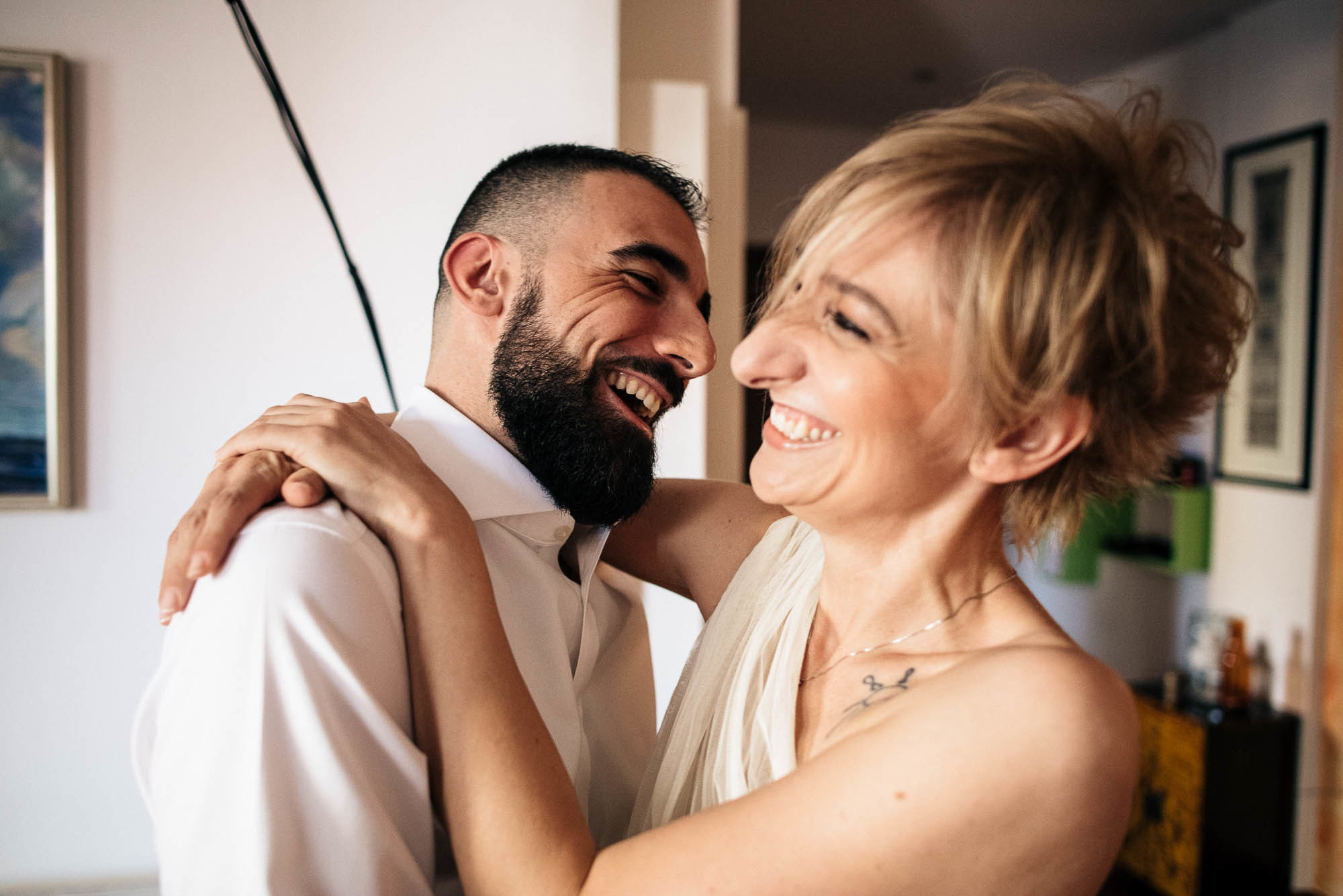 Смеющиеся жених и невеста обнимают друг друга в комнате, свадьба в Италии