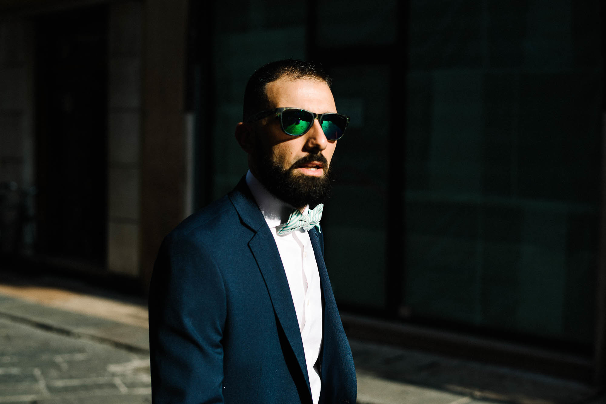 Жених в костюме и солнцезащитных очках во время свадебной фотосессии на площади в Вероне, Италия