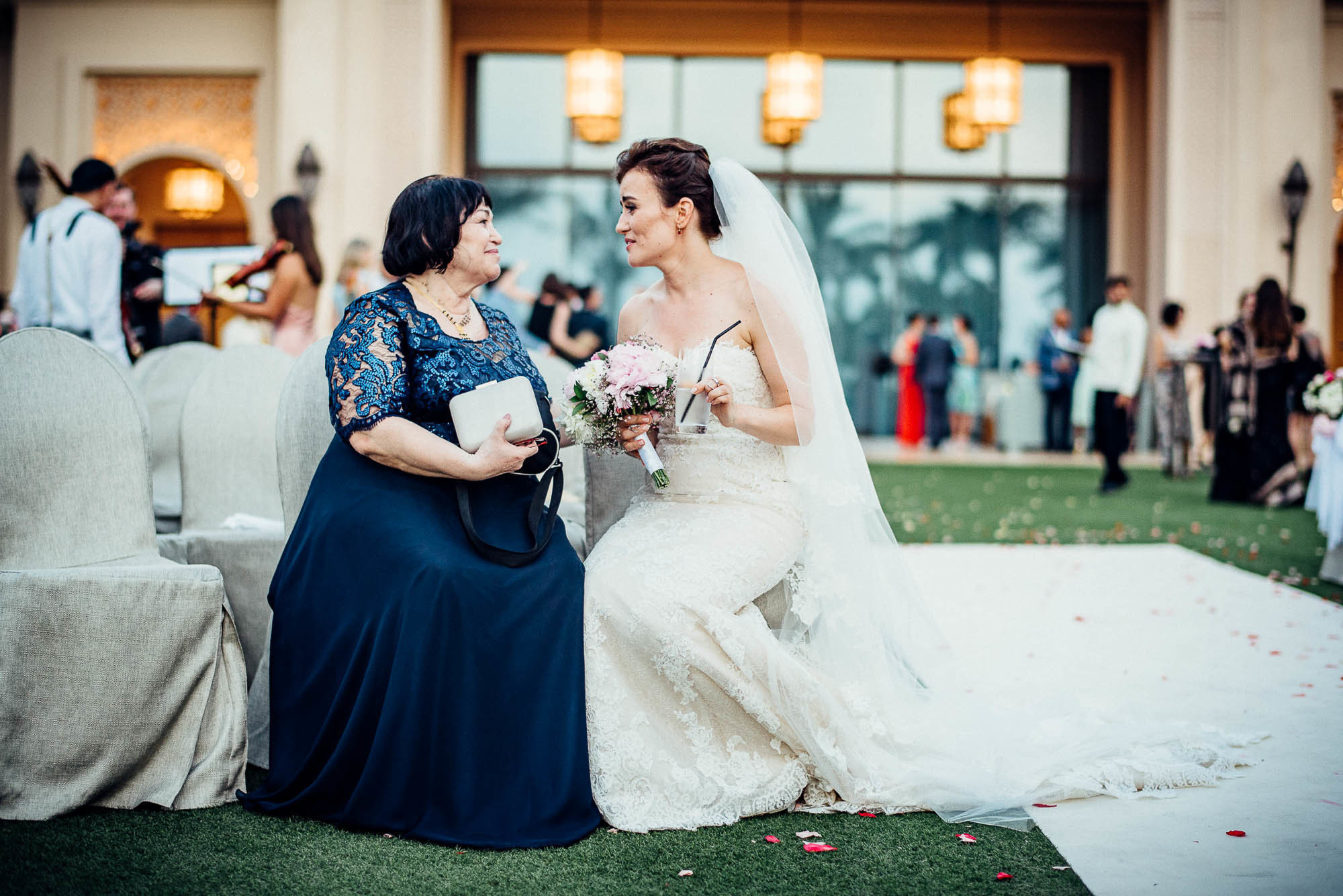 Счастливые невеста и мама сидят рядом на стульях, свадебная фотосессия