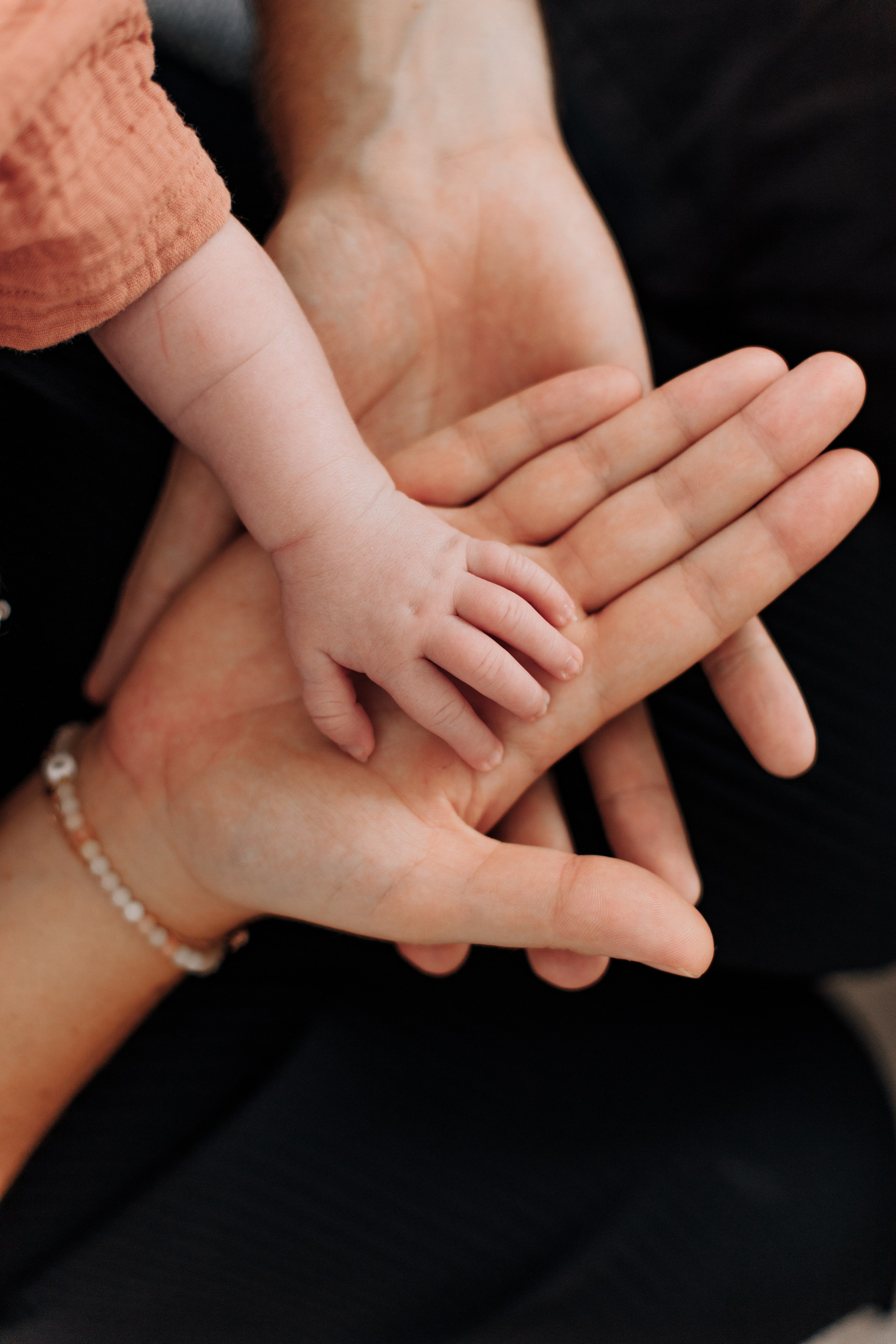 Die Hand des Babys liegt auf den Händen von Mutter und Vater.