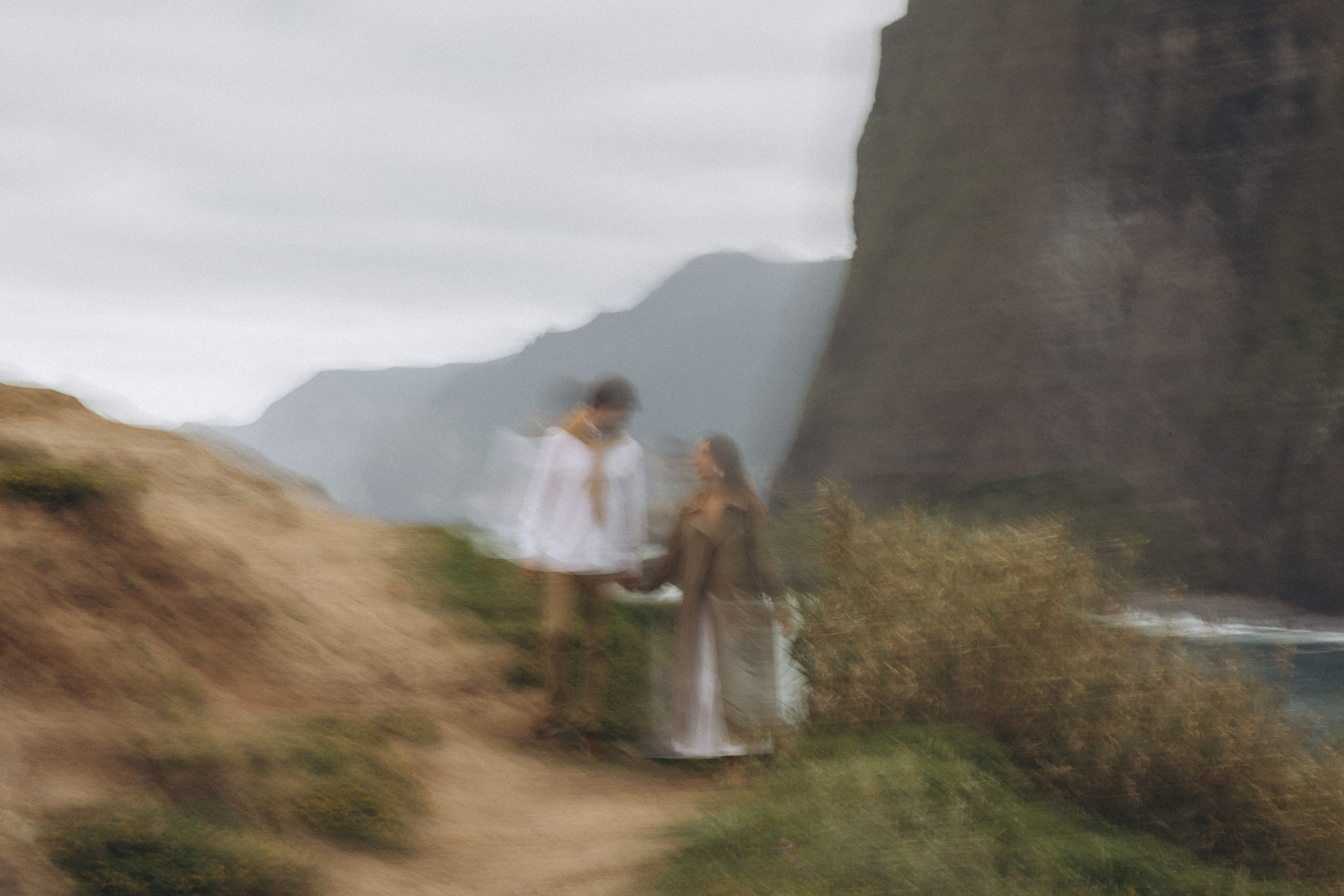 Beautiful engagement moment by the ocean in Madeira, Portugal, as one partner kneels to propose while waves crash in the background.