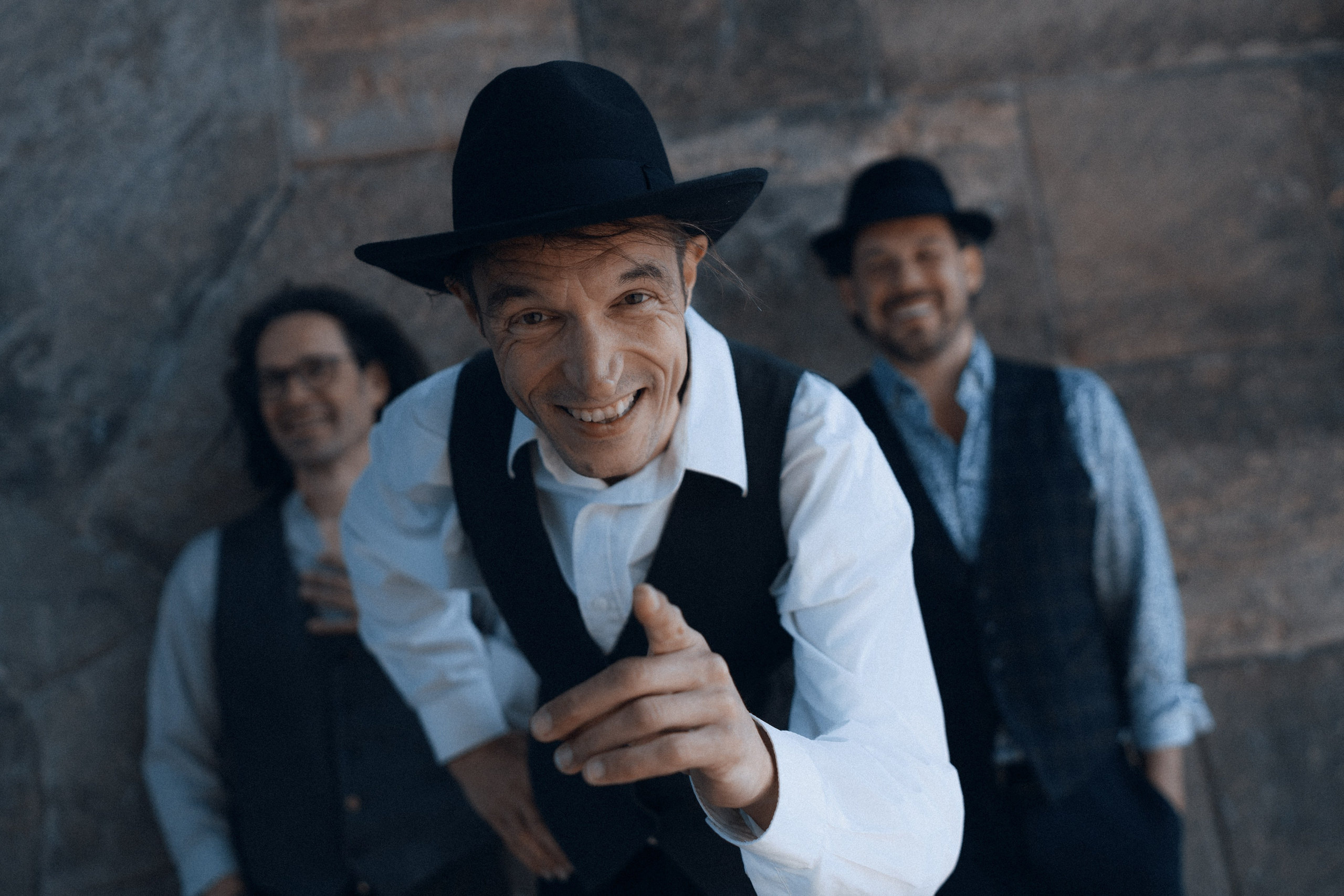 Nahaufnahme des Geigers mit schwarzem Hut, Bandkollegen im Hintergrund