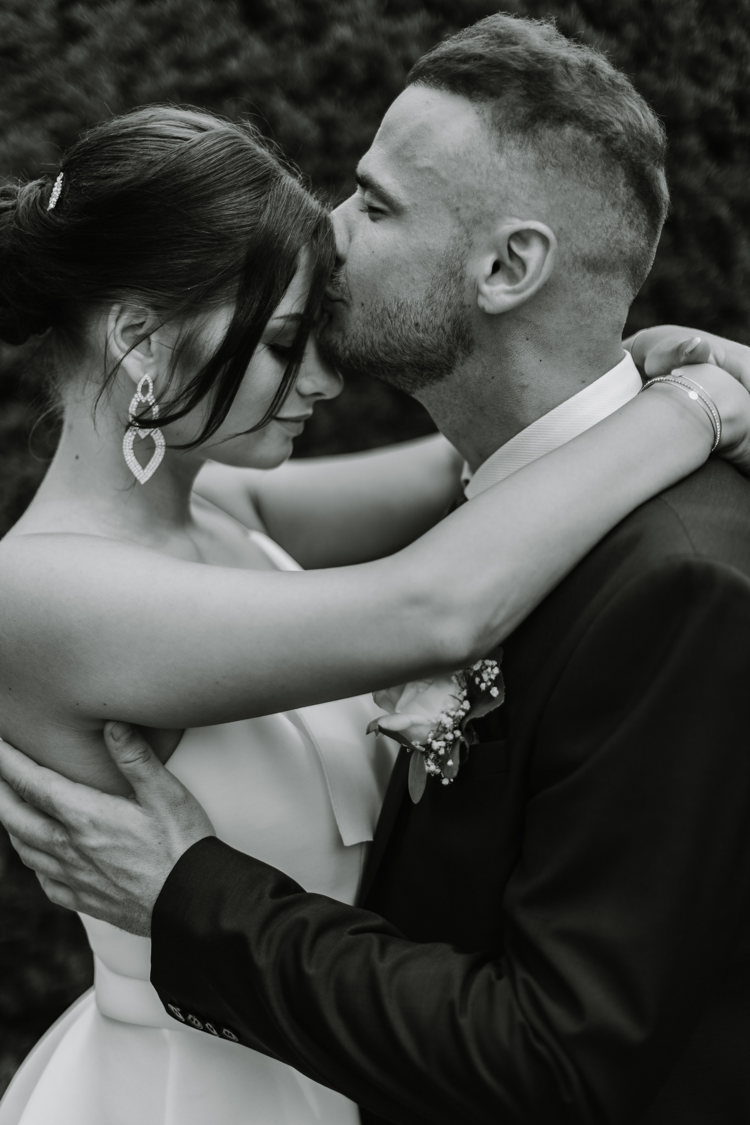 Bräutigam küsst Braut liebevoll auf die Stirn.