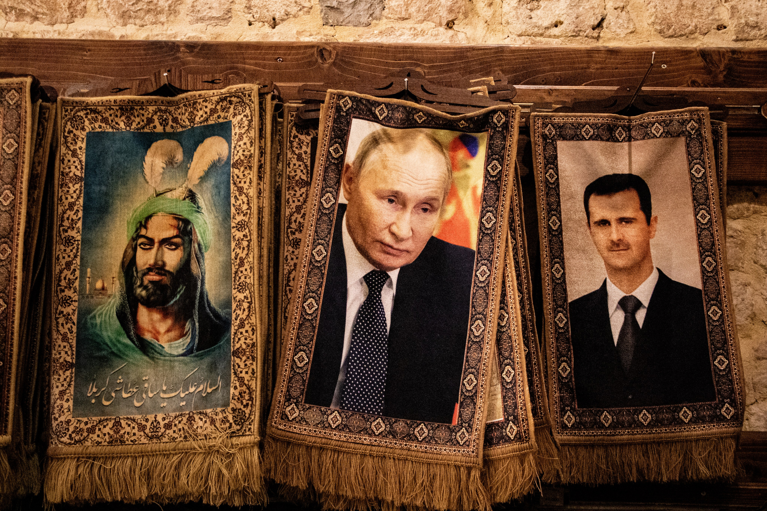 Trois tapis dans un souk, dont deux représentant Vladimir Poutine et Bachar al-Assad, symbolisent la présence et l’influence croissante de la Russie en Syrie, renforcées par ses liens étroits avec le régime syrien depuis le début du conflit.