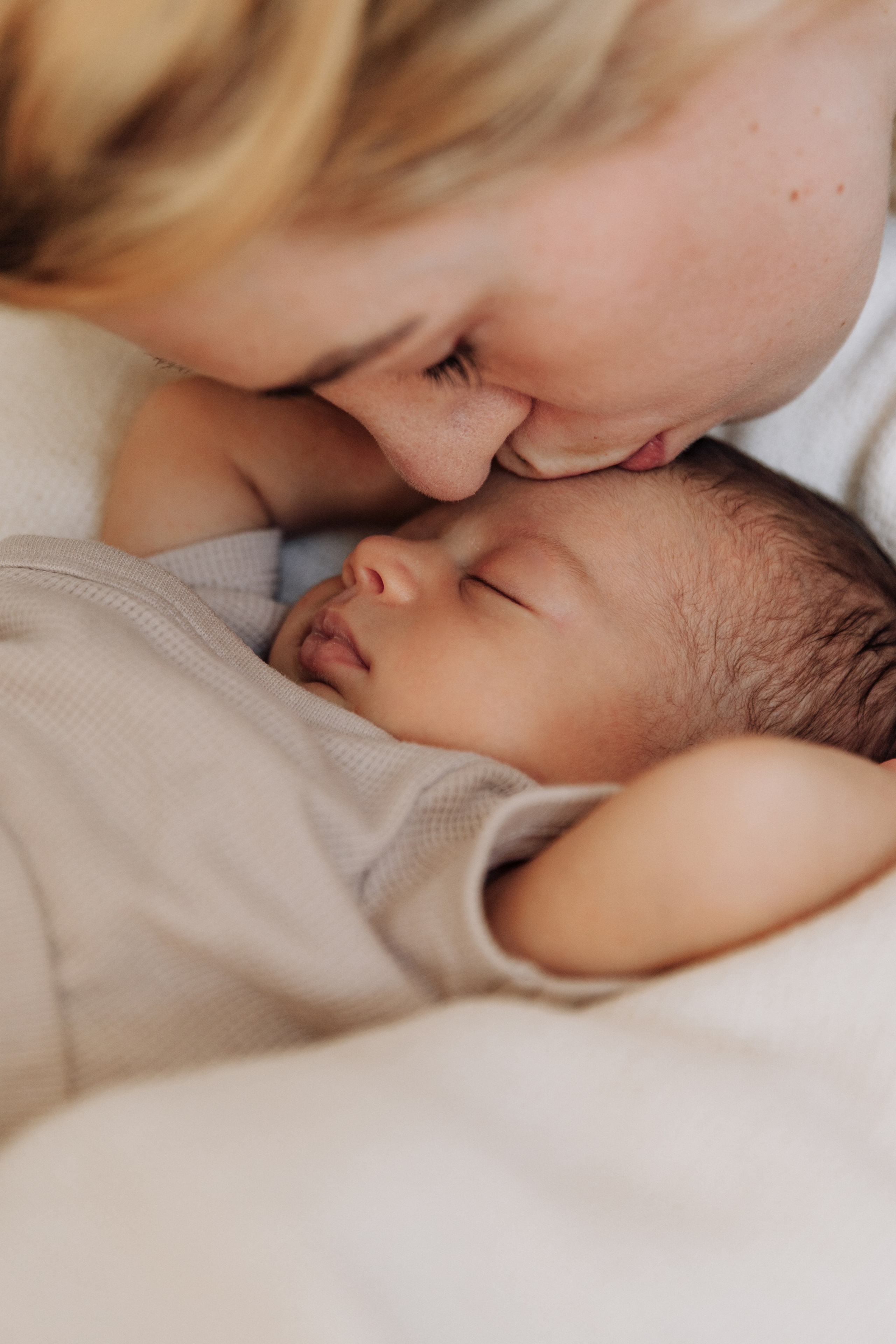 Mutter küsst ihre schlafende Tochter sanft auf die Stirn.