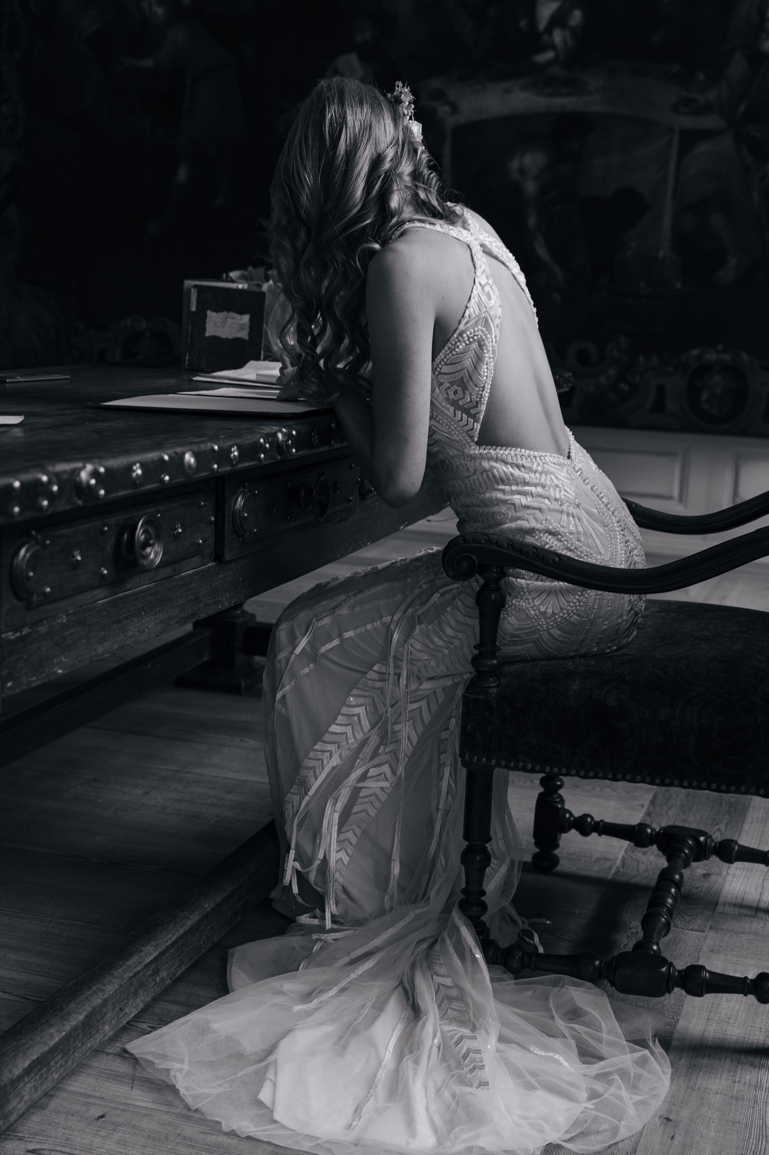 Braut sitzt auf einem antiken Stuhl und unterschreibt Hochzeitsdokumente bei der Anmeldung der Eheschließung im Standesamt Seligenstadt.