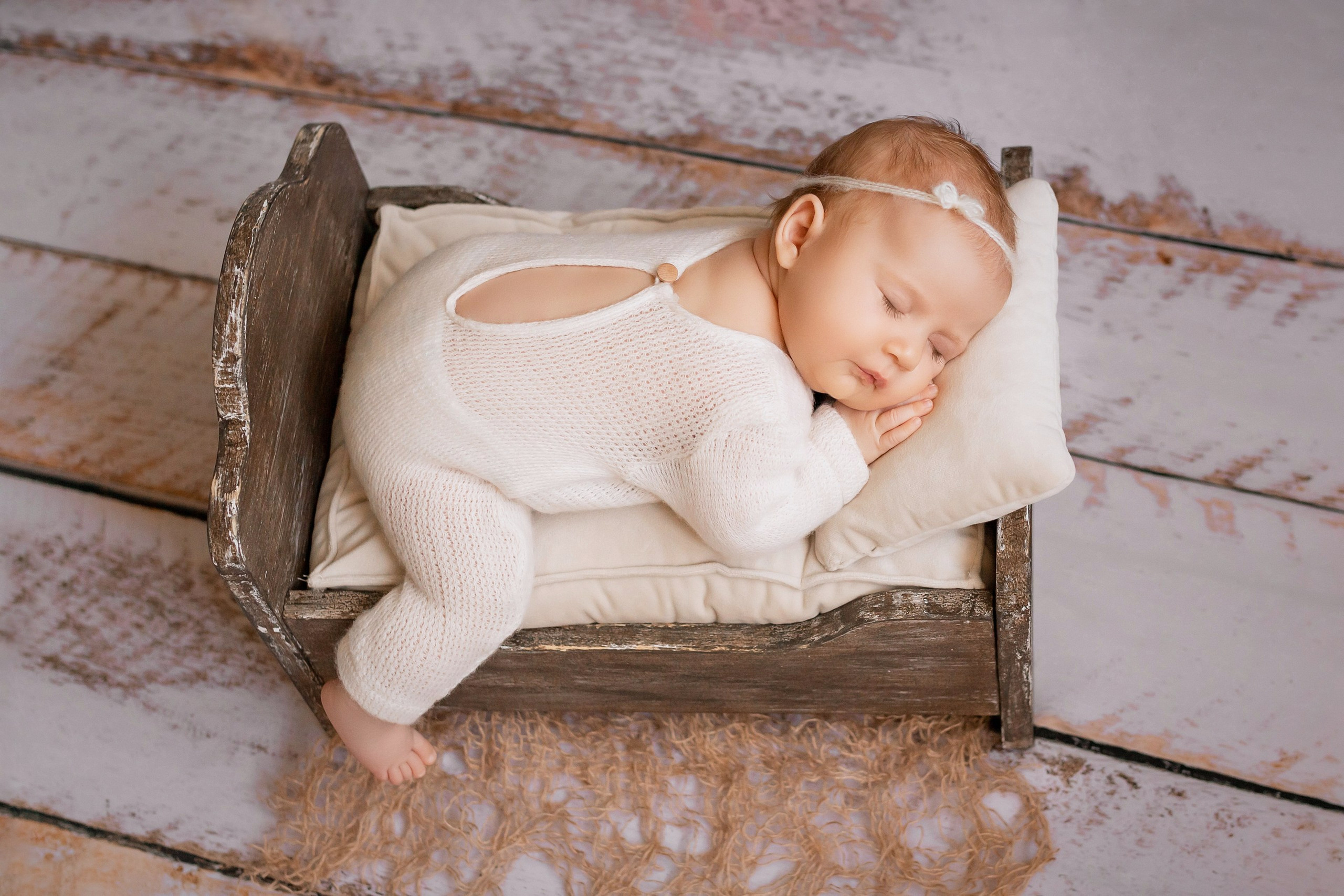 Newborn baby girl sleeping soundly in wooden cradle