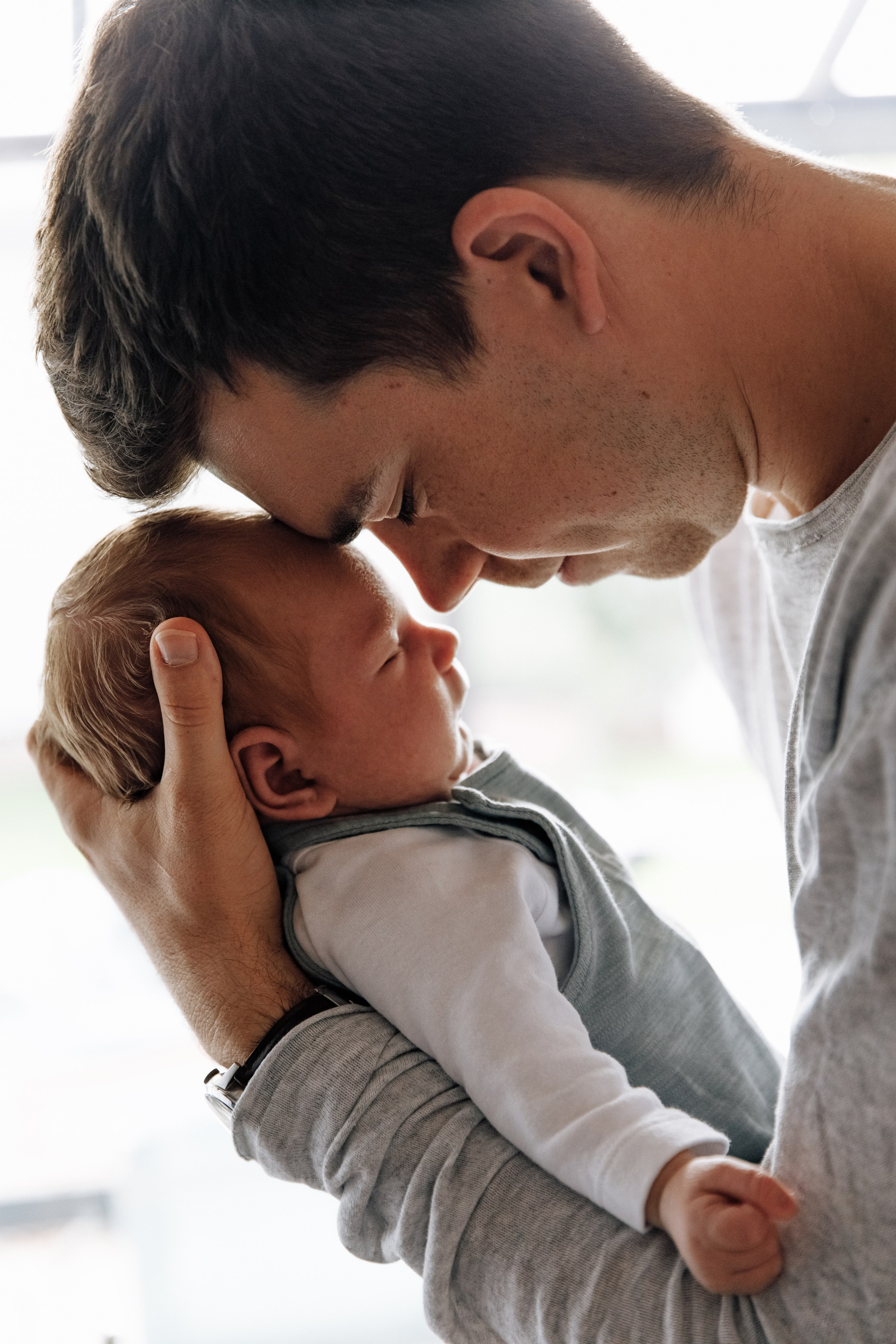 Papa berührt liebevoll mit der Stirn das Baby.