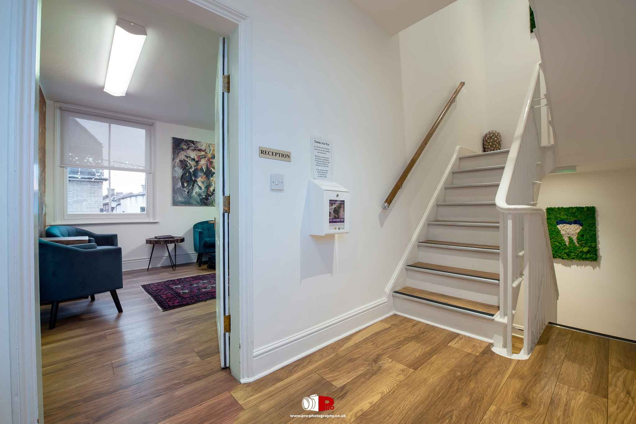 Bright and welcoming dental clinic reception area featuring wooden flooring, modern furniture, and decorative art.